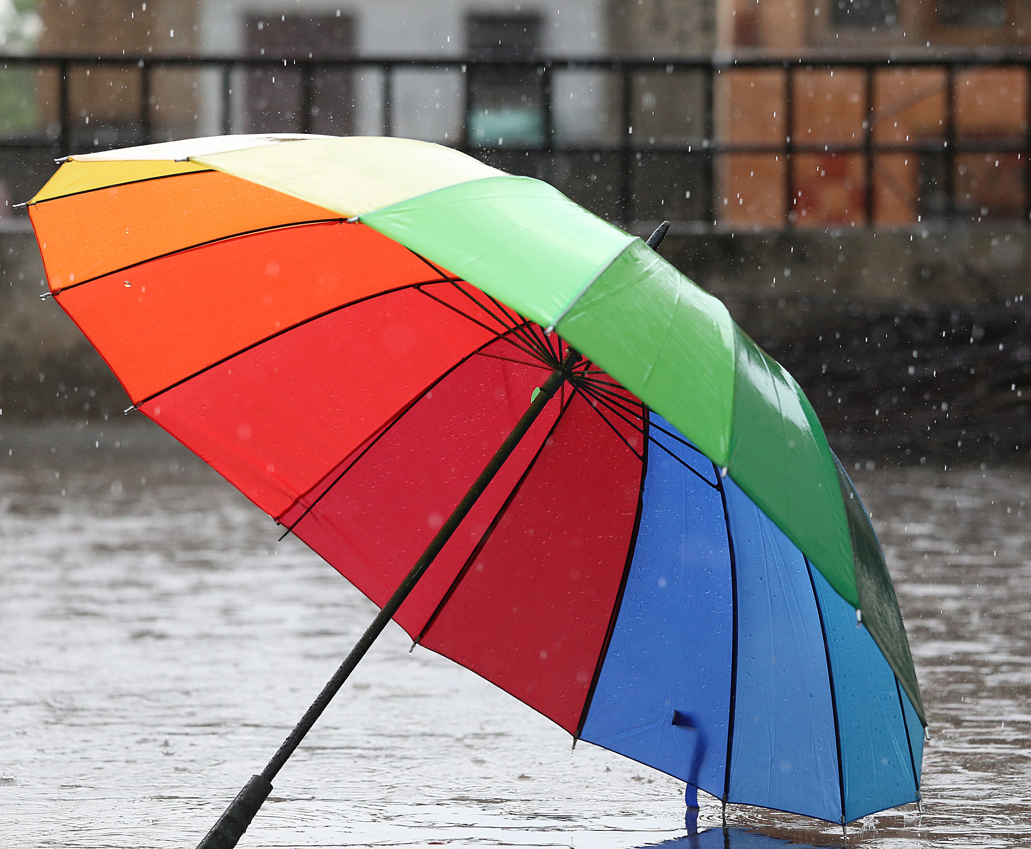 multi-colored umbrella on sidewalk in rain