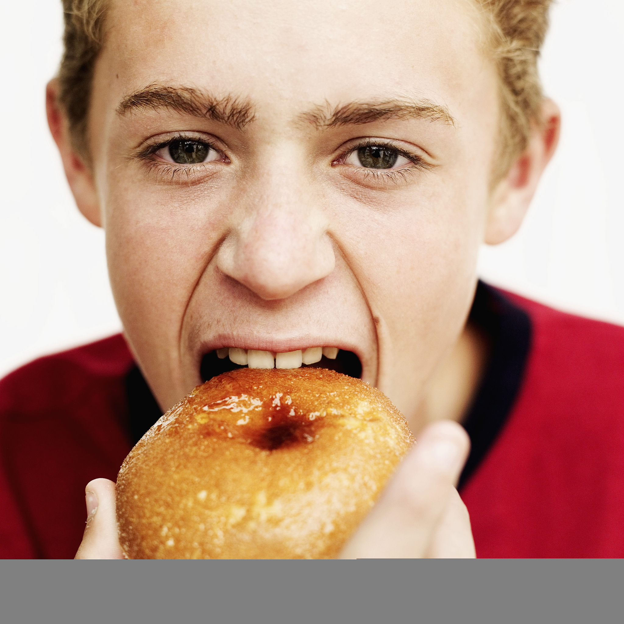 close-up of a teenage boy (15-17) biting into a doughnut