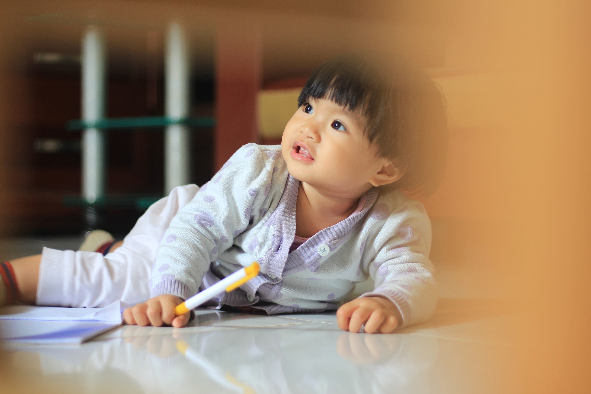 girl holding pen while lying on floor