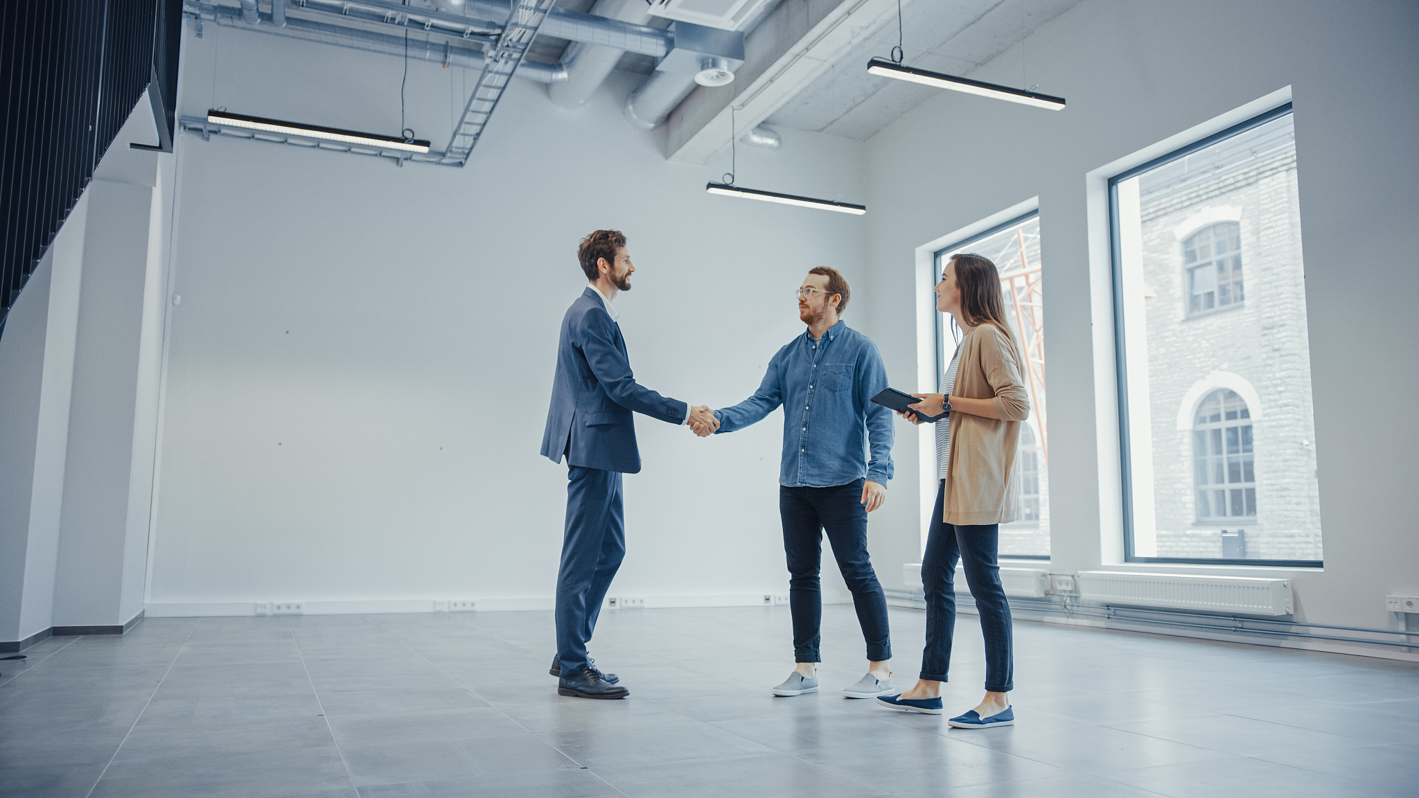 real estate agent showing a new empty office space to young male