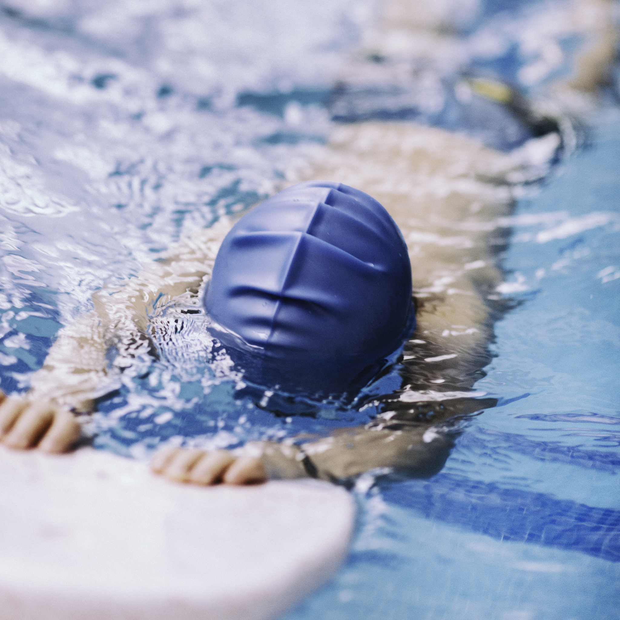 little boy swimming with kicking board