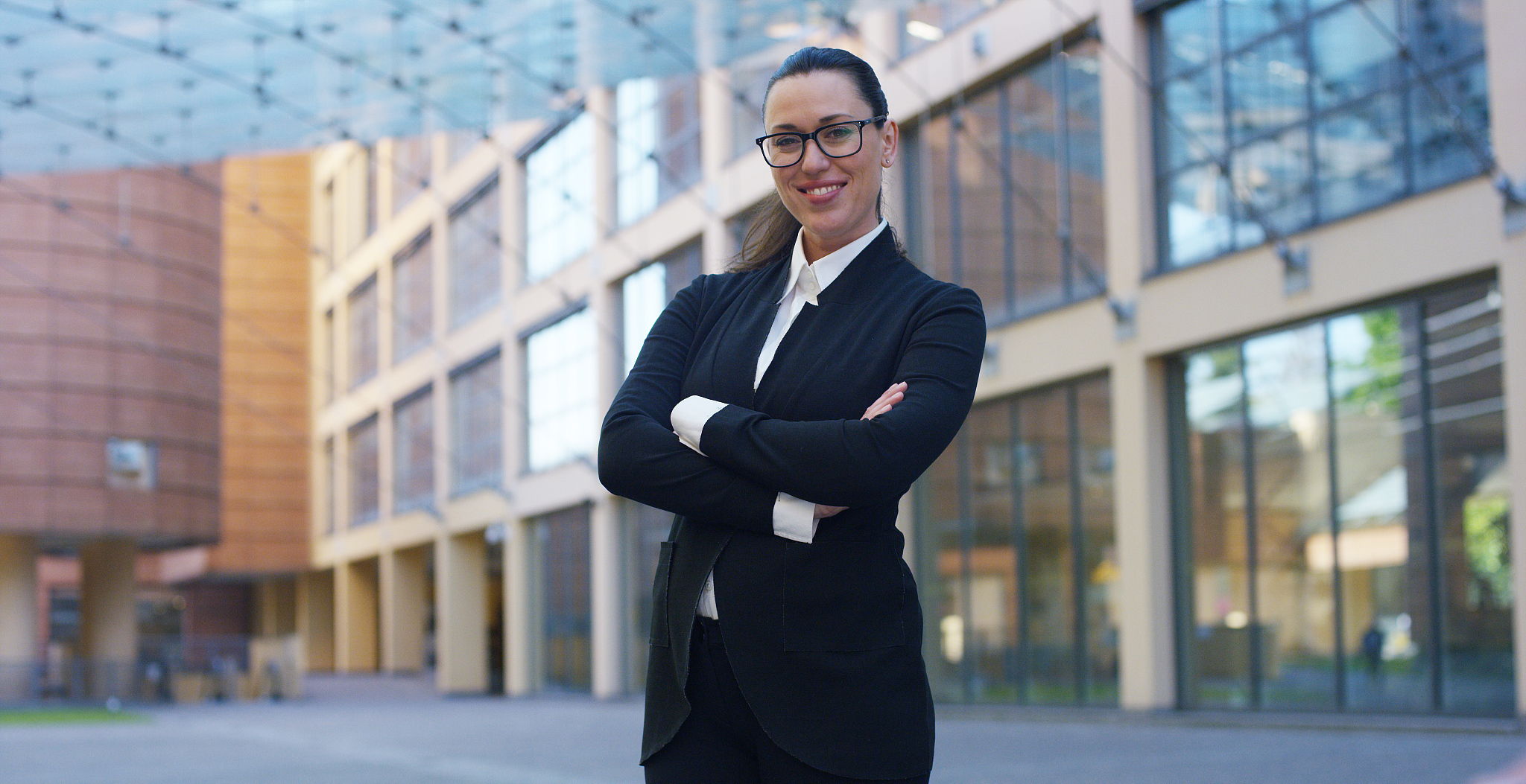 a woman in a suit, looks in camera and smiles proud and sure of 