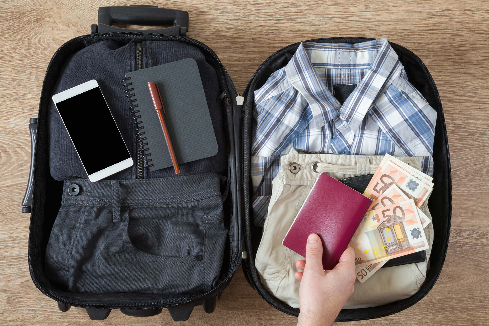 man packing a different things into a travel bag for business tr