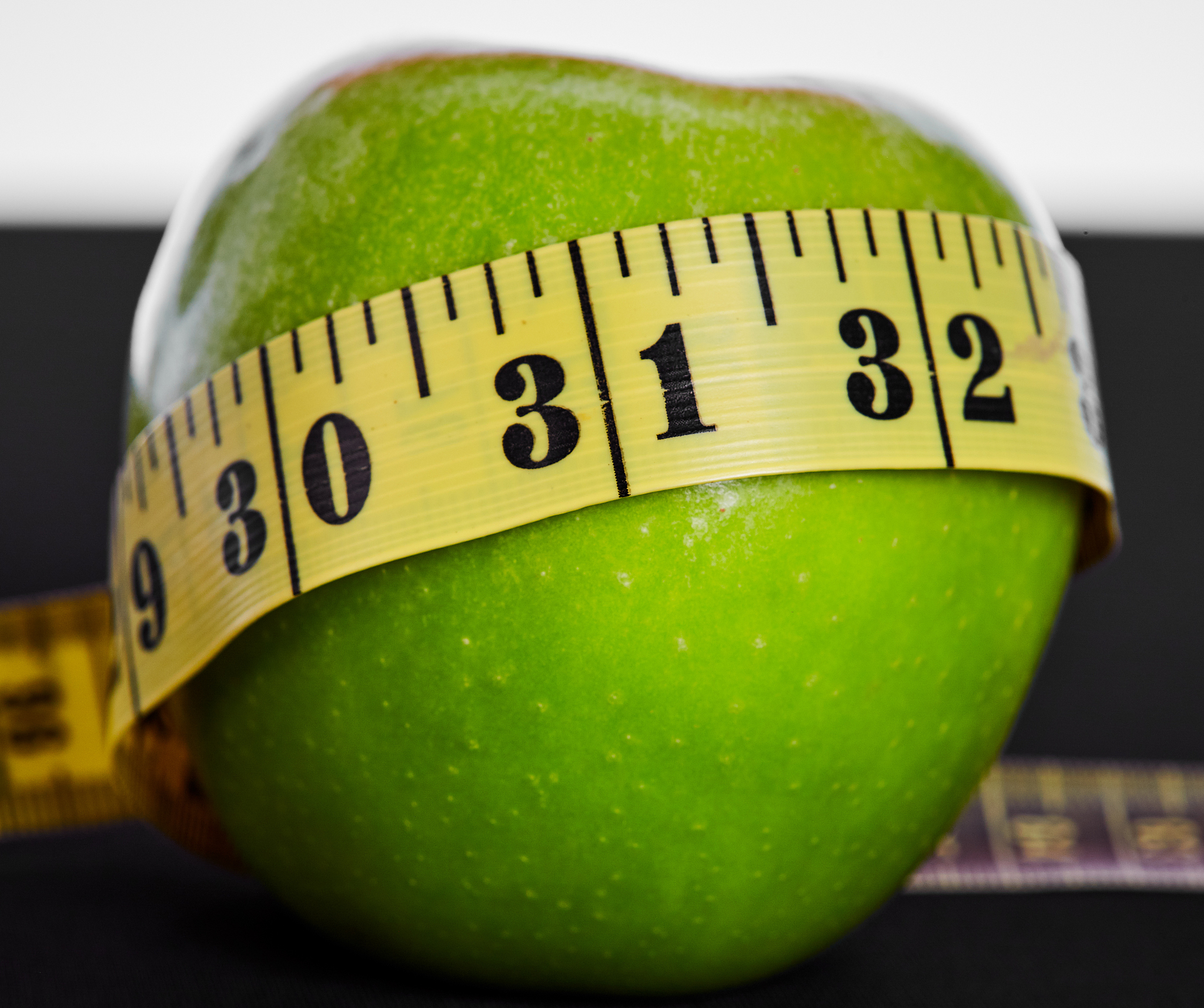 granny smith apple wrapped in tape measure
