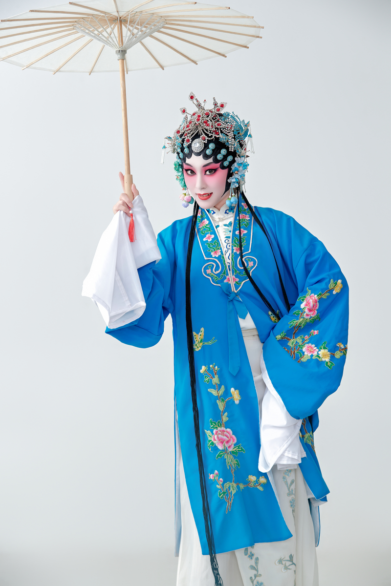 一位扮演青衣或花旦角色的京剧女演员,手持油纸伞.