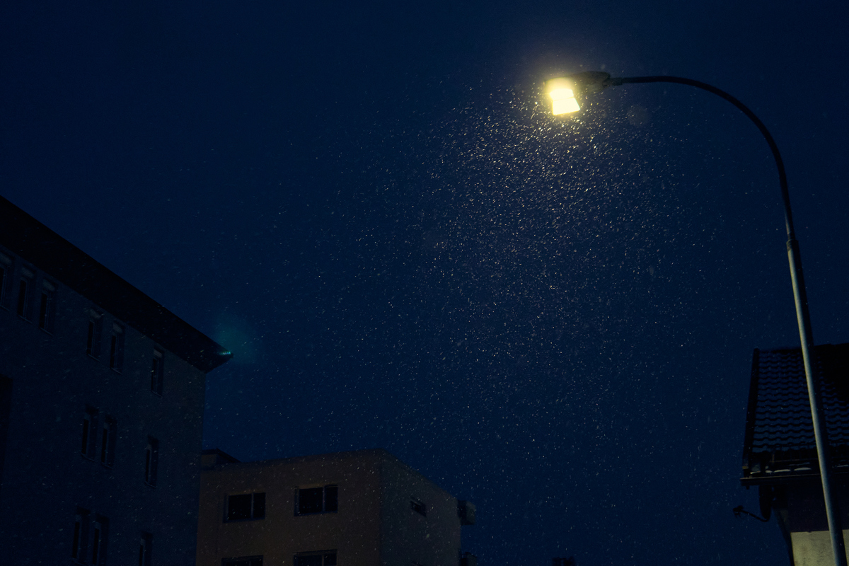 夜晚,宁静的城市区域,背景是建筑,路灯下正下着雨