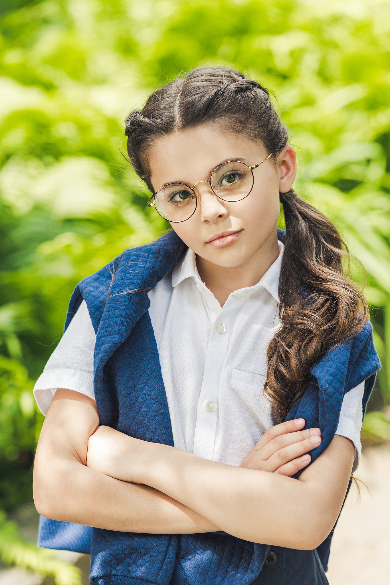 serious schoolgirl with crossed arms in white shirt and jumper o