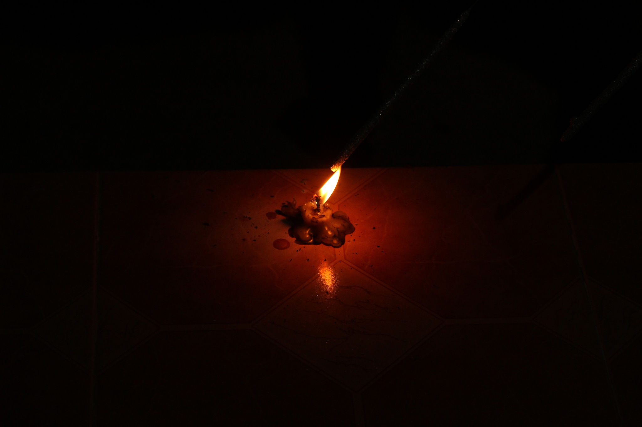 single half melted burning candle on the dark background or blac