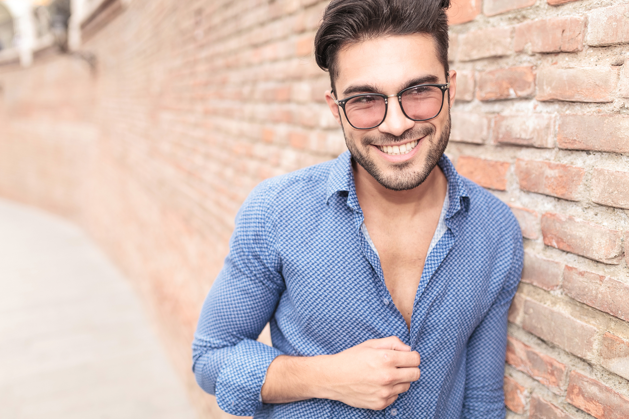 man with glasses looks to side and laughs