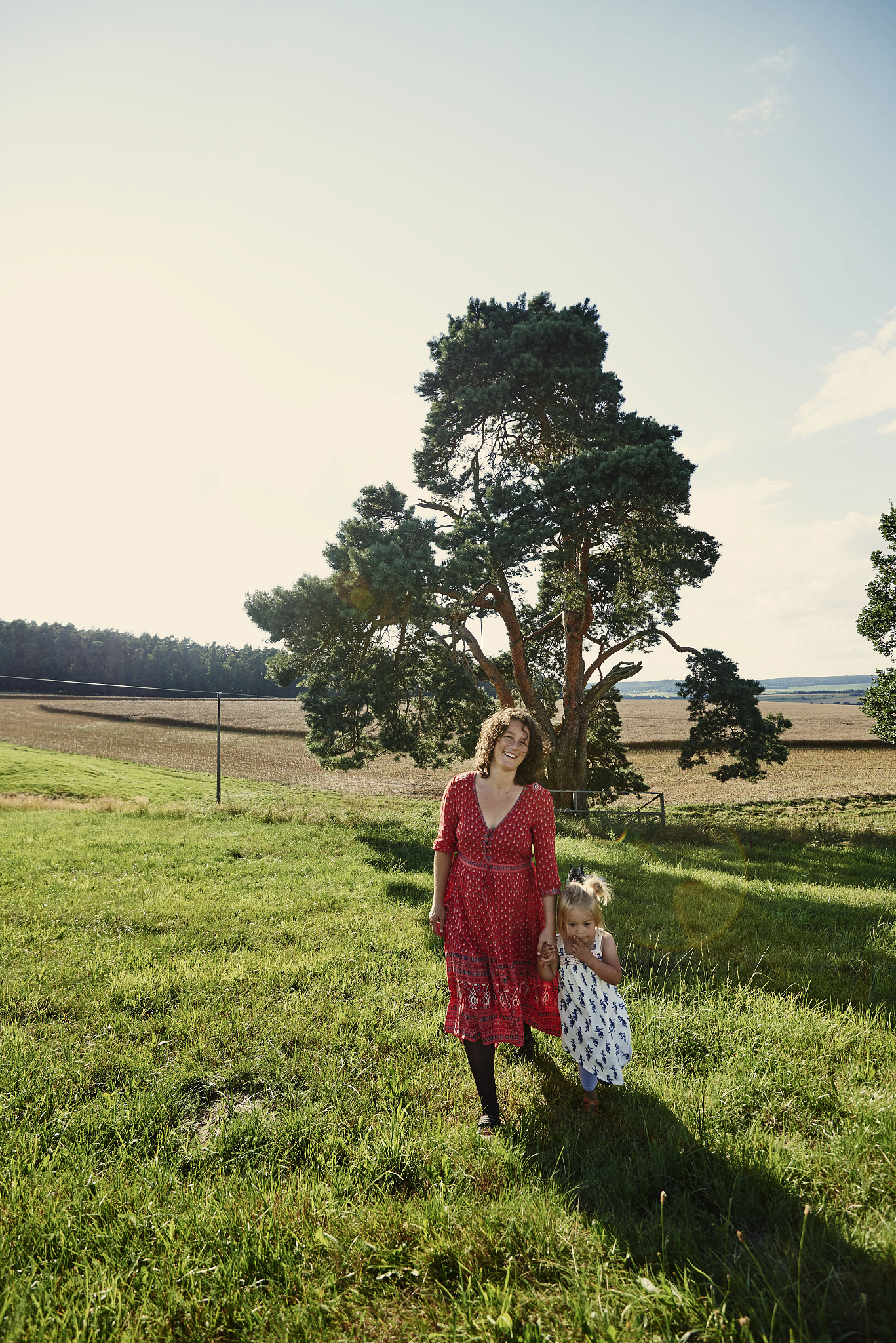 portrait of pregnant woman and toddler daughter in field landsca