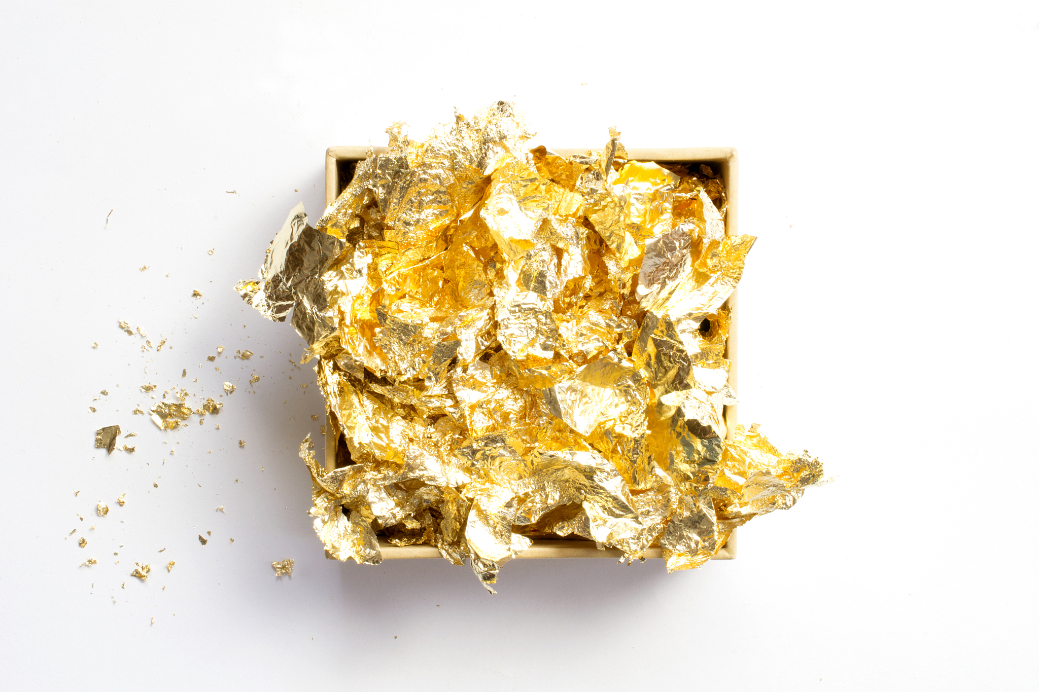 golden foil pieces in the opened cardboard box with crumbs by si