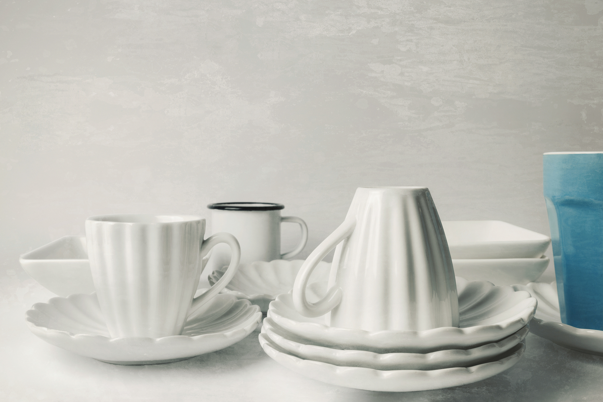 close-up of white ceramic coffee cups, wall in the background