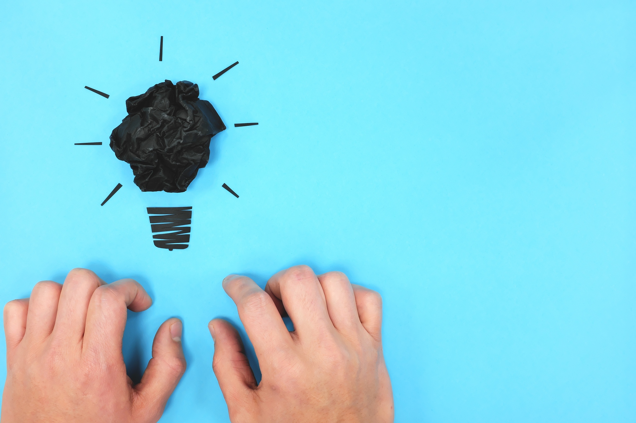 black light bulb with hands in blue background flat lay. drained