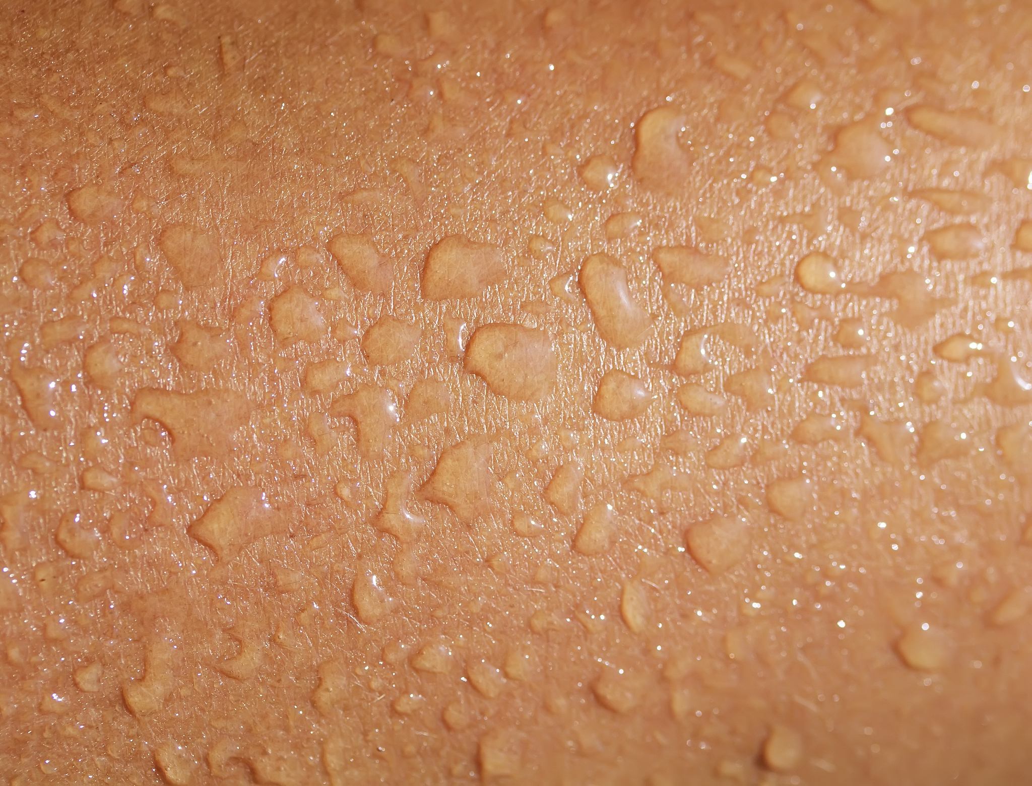 texture of tanned human skin is covered with large drops of fres