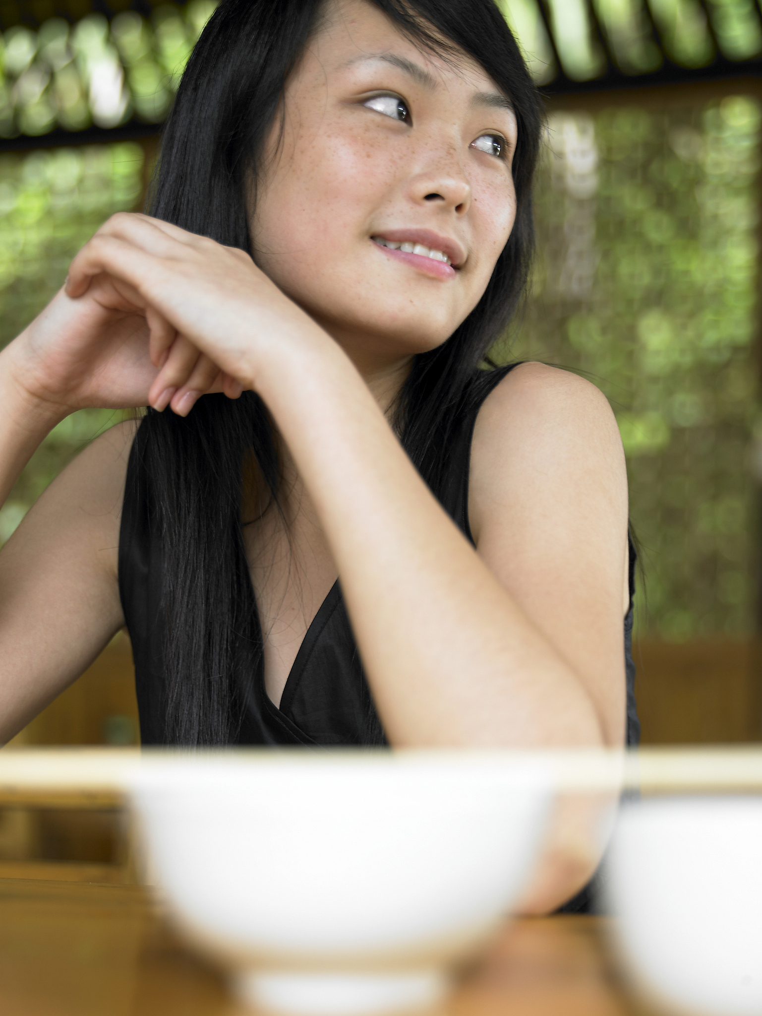 young woman sitting at table, looking off to side