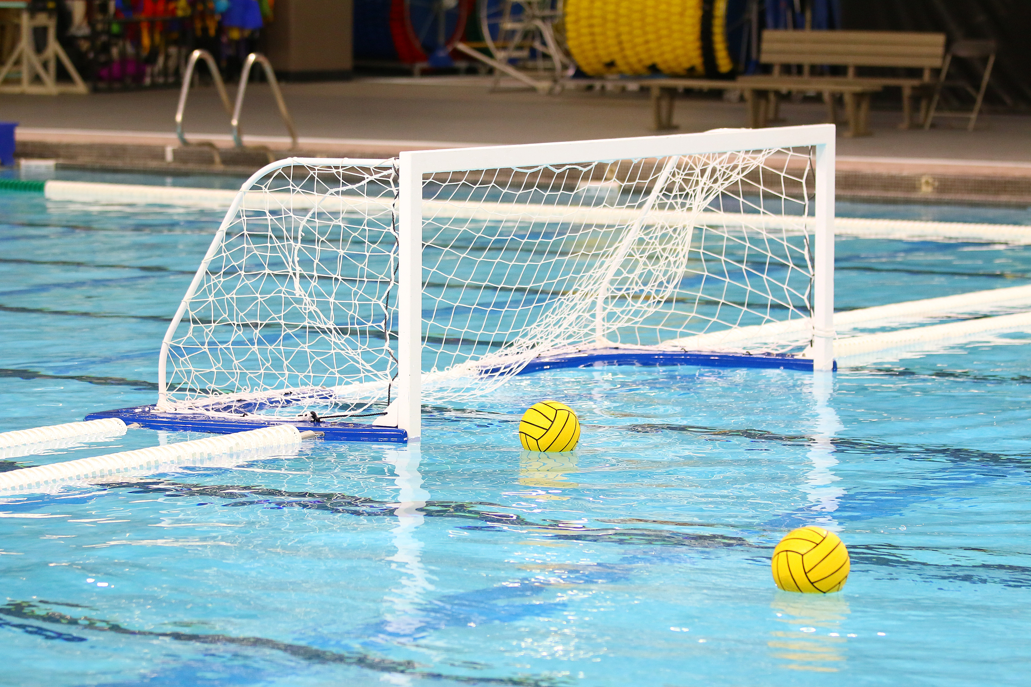 two yellow water polo balls floating on the water near the goal 