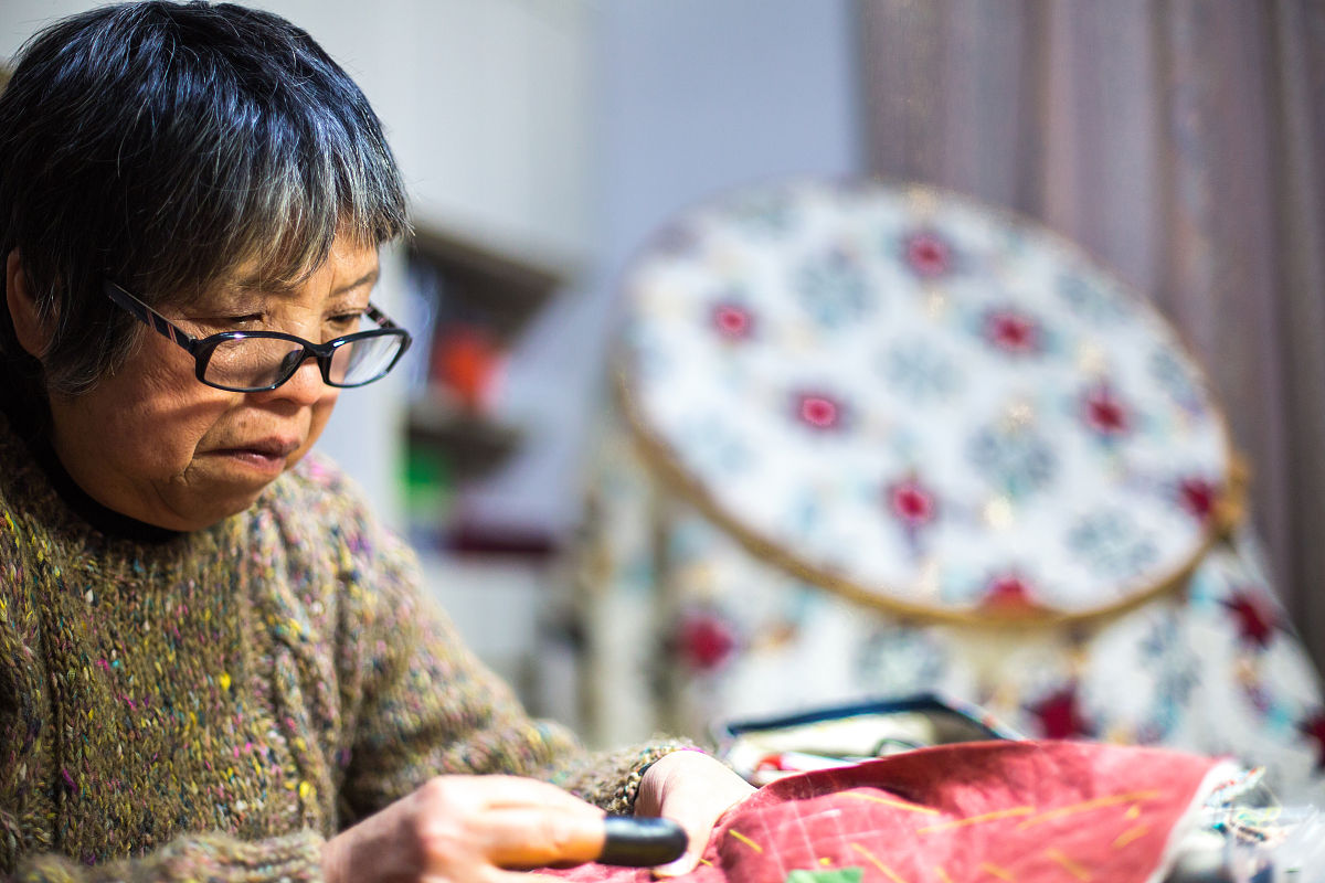 一位年长妇女在她的家中缝纫和制作工艺品
