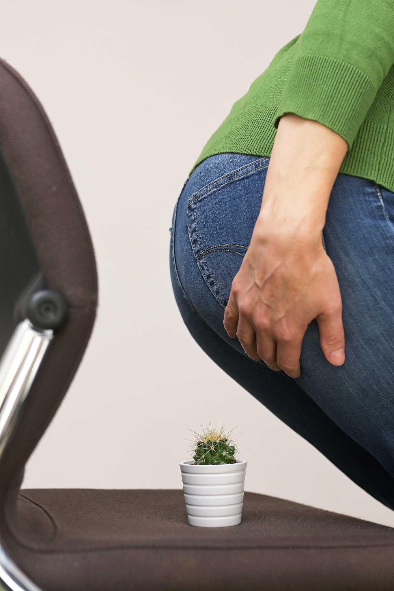 woman suffering from hemorrhoids and thorny cactus on chair