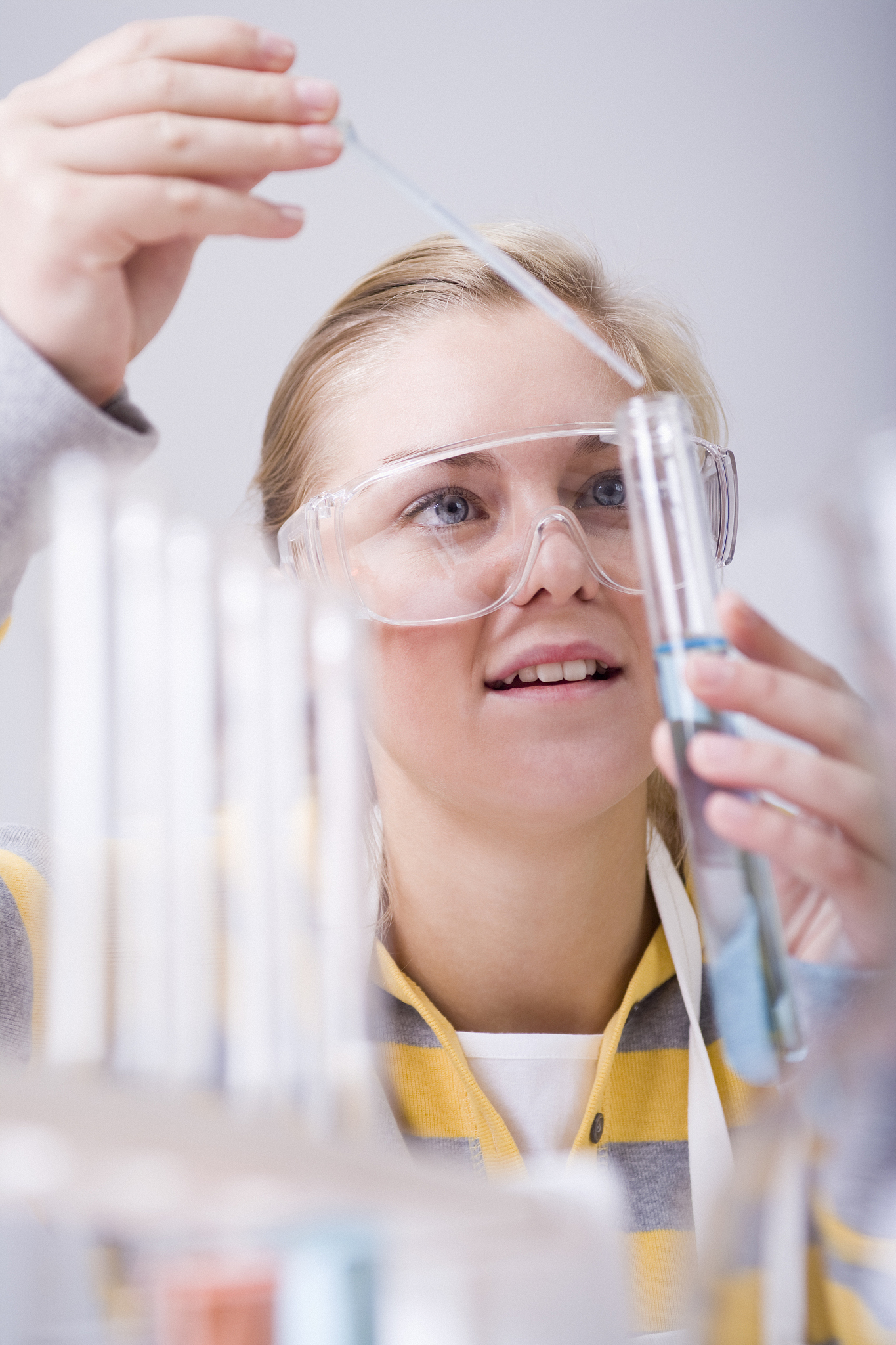 teenage girl pouring liquid into test tube