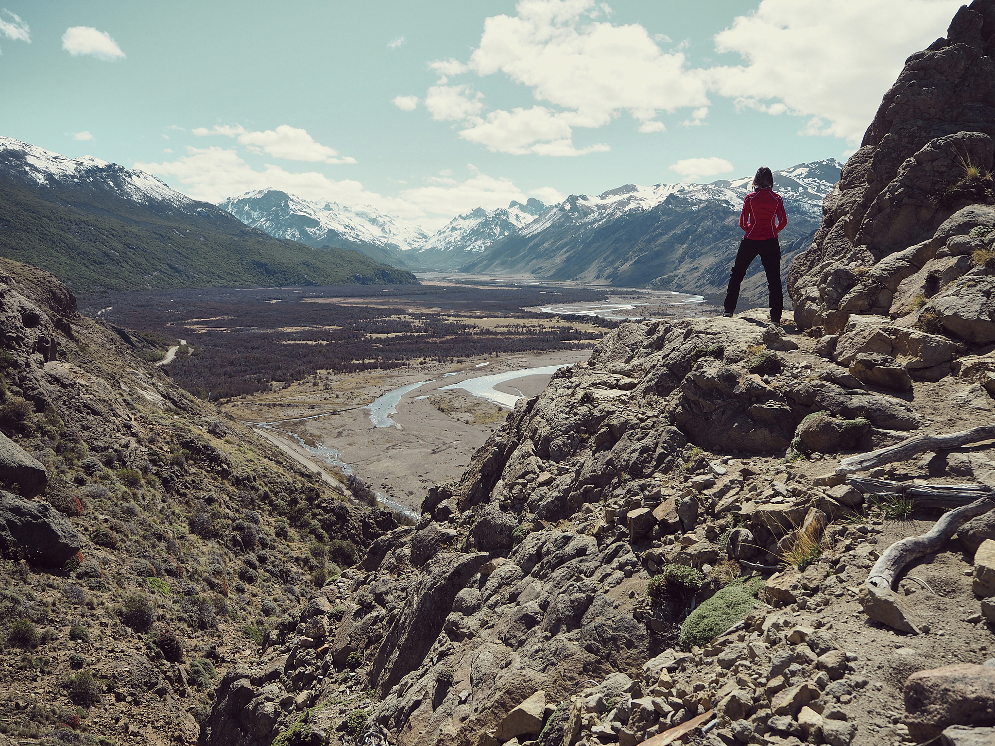 full length rear view of woman standing on a rock admiring the m