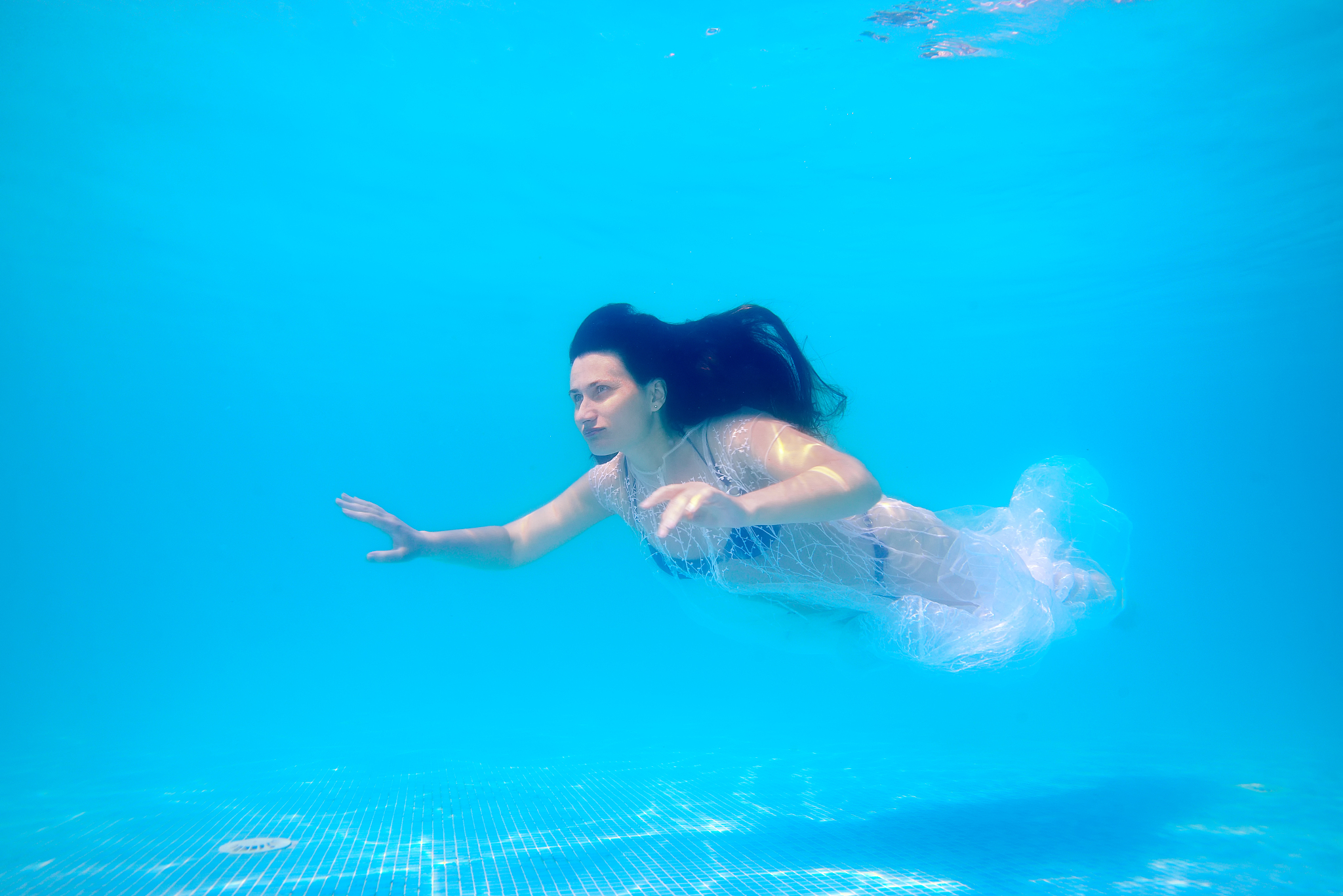 a beautiful sporty girl is swimming underwater in a blue swimsui