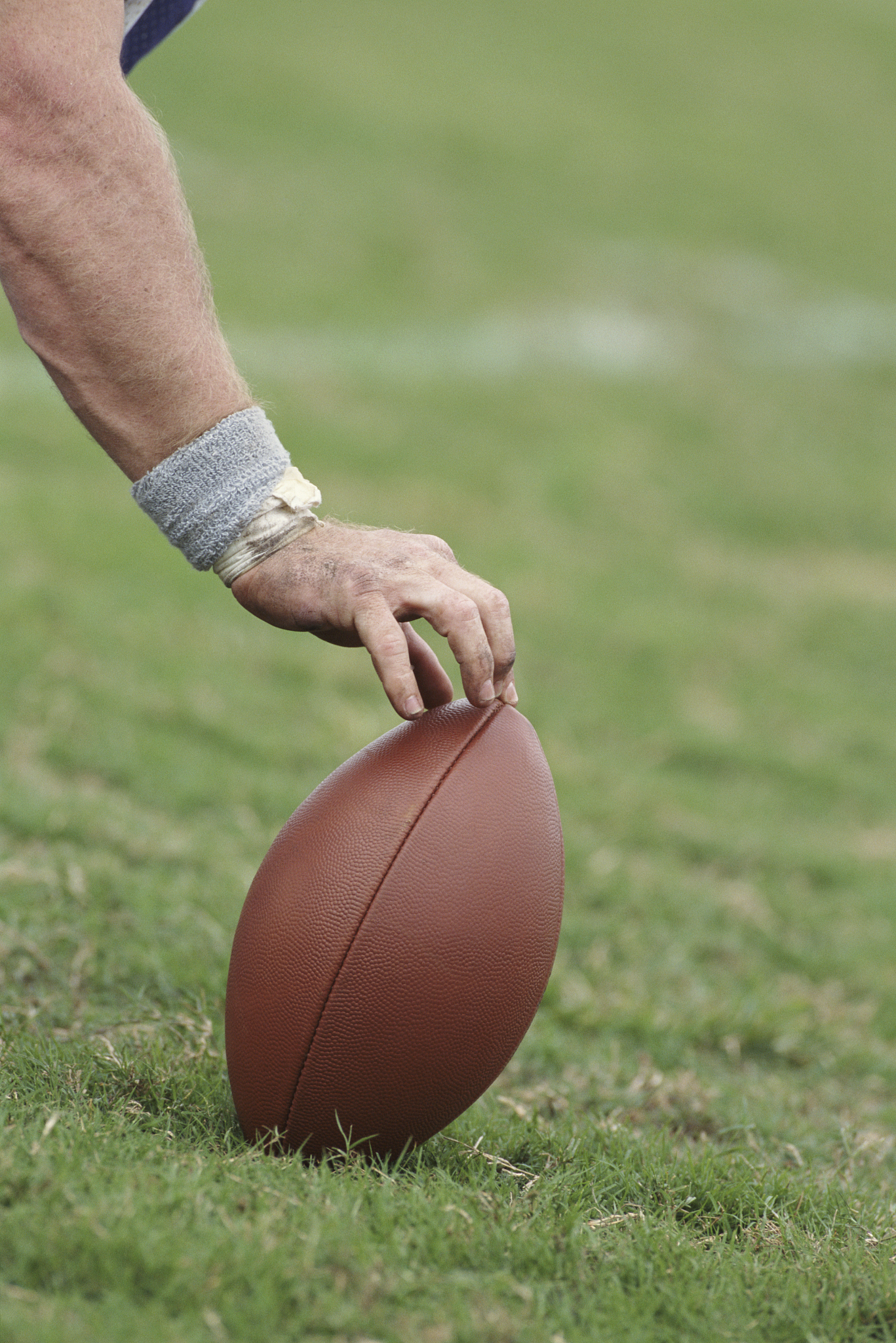 football player balancing ball for kicker, close-up