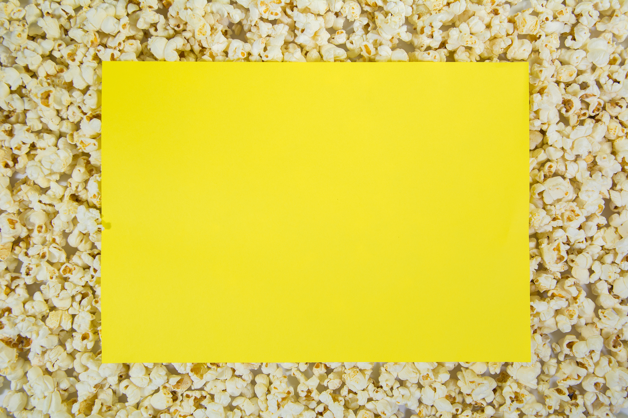 top angle shot of popcorn with a yellow color paper frame