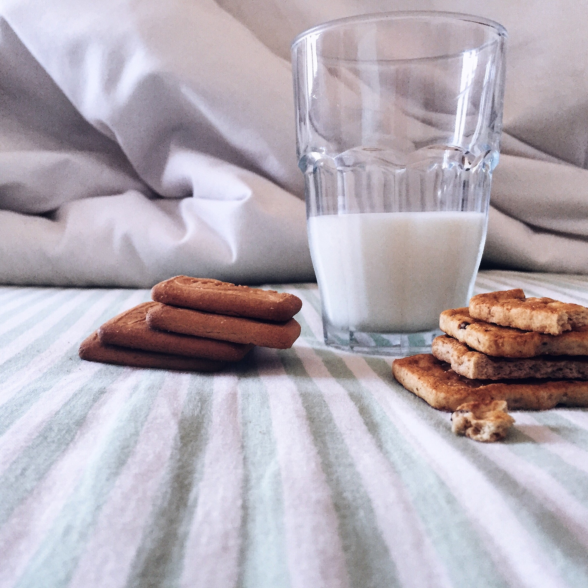 cookies and glass of milk on bed