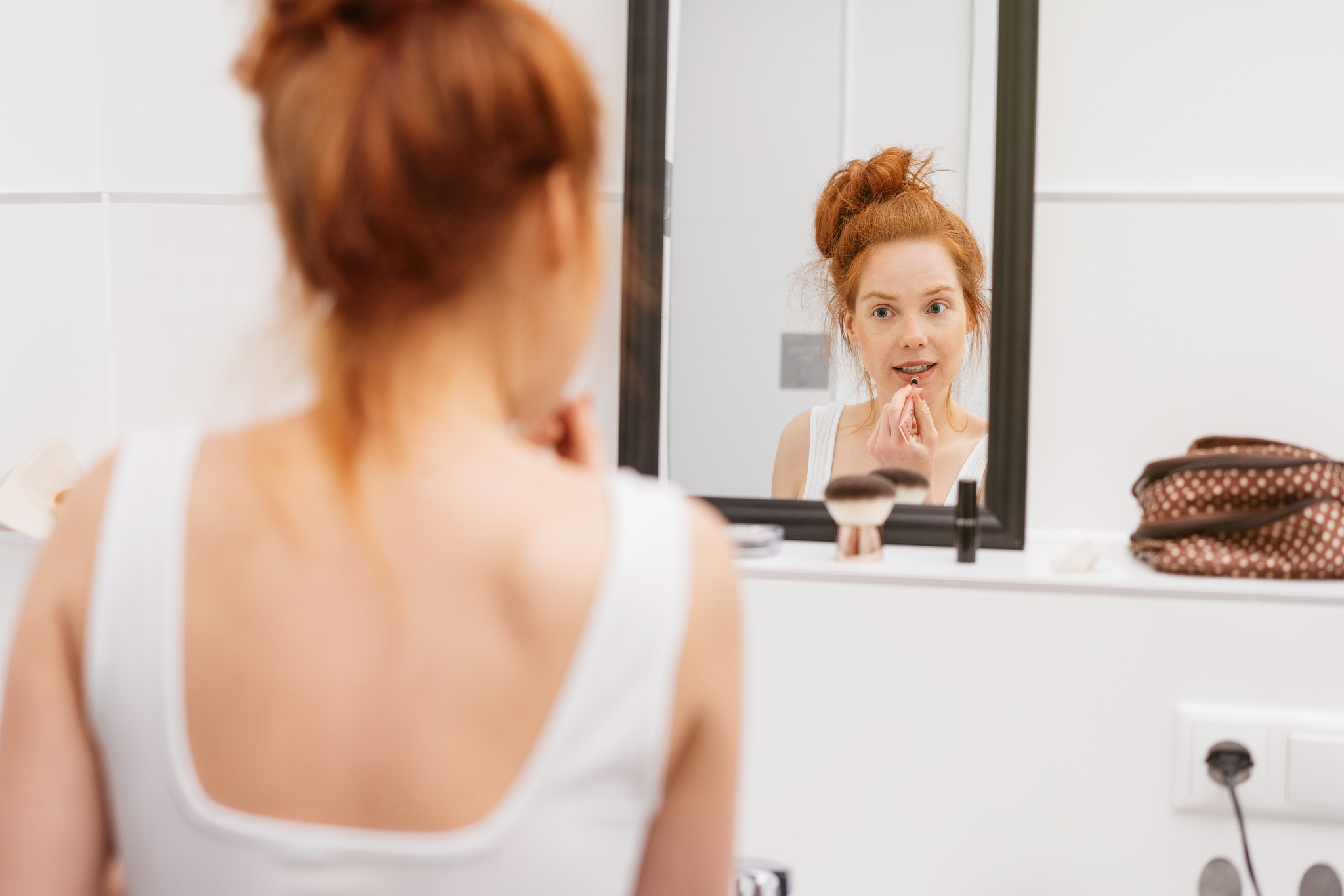 pretty young redhead woman applying lipstick