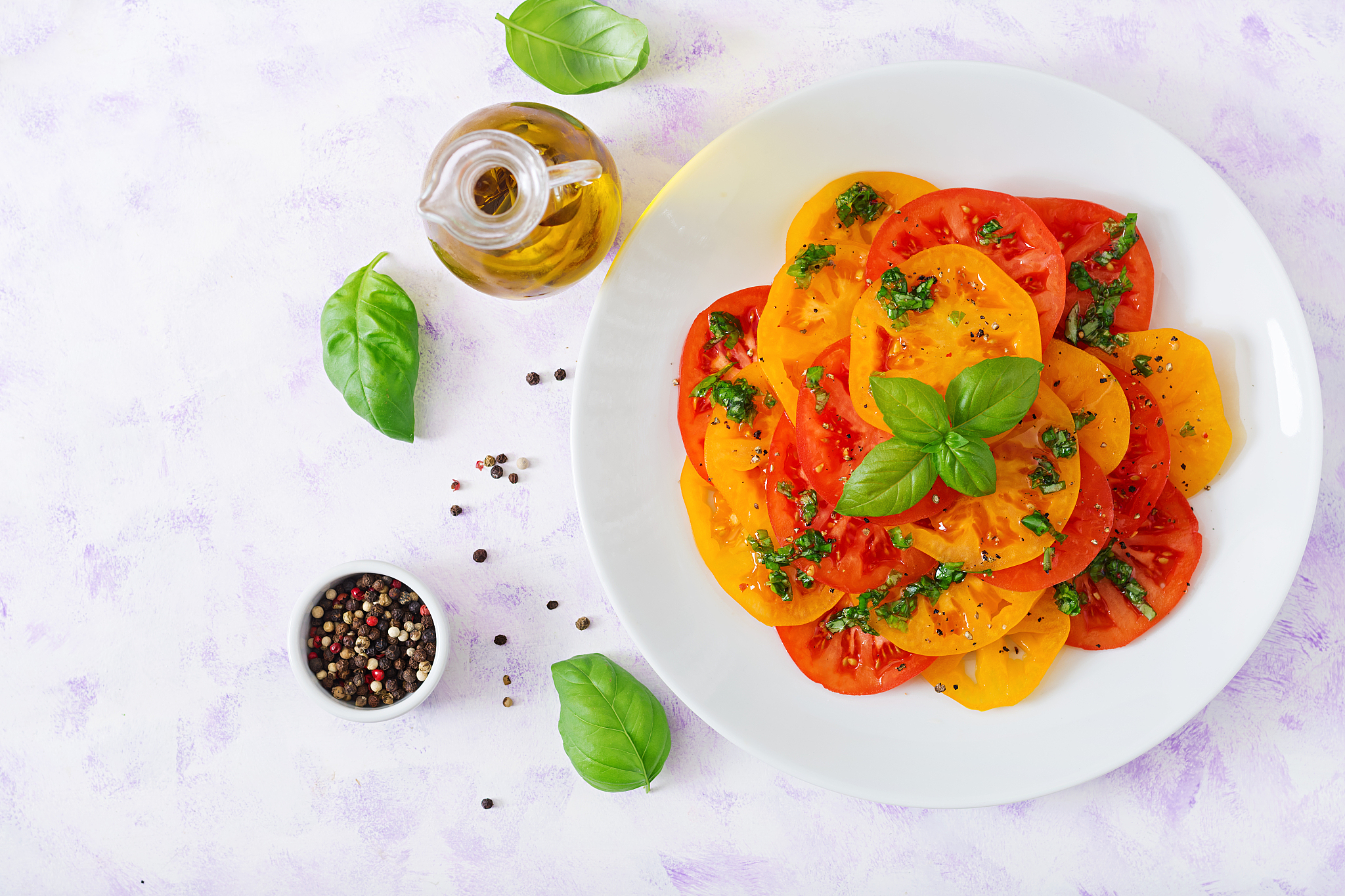 salad of yellow and red tomato with basil pesto on a light backg