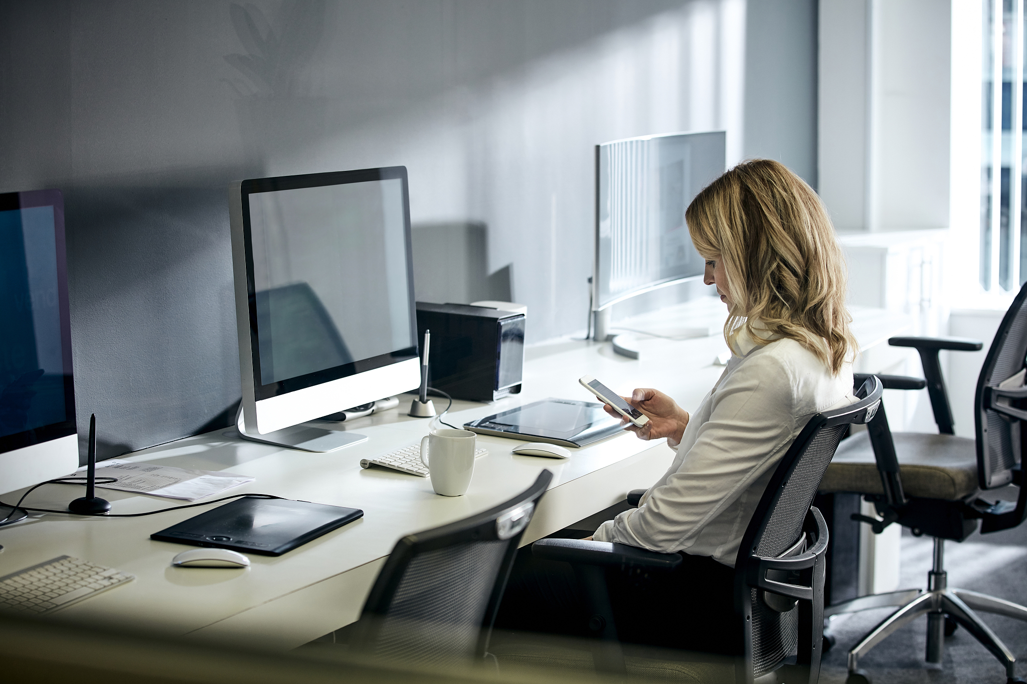 female using phone and computer in office