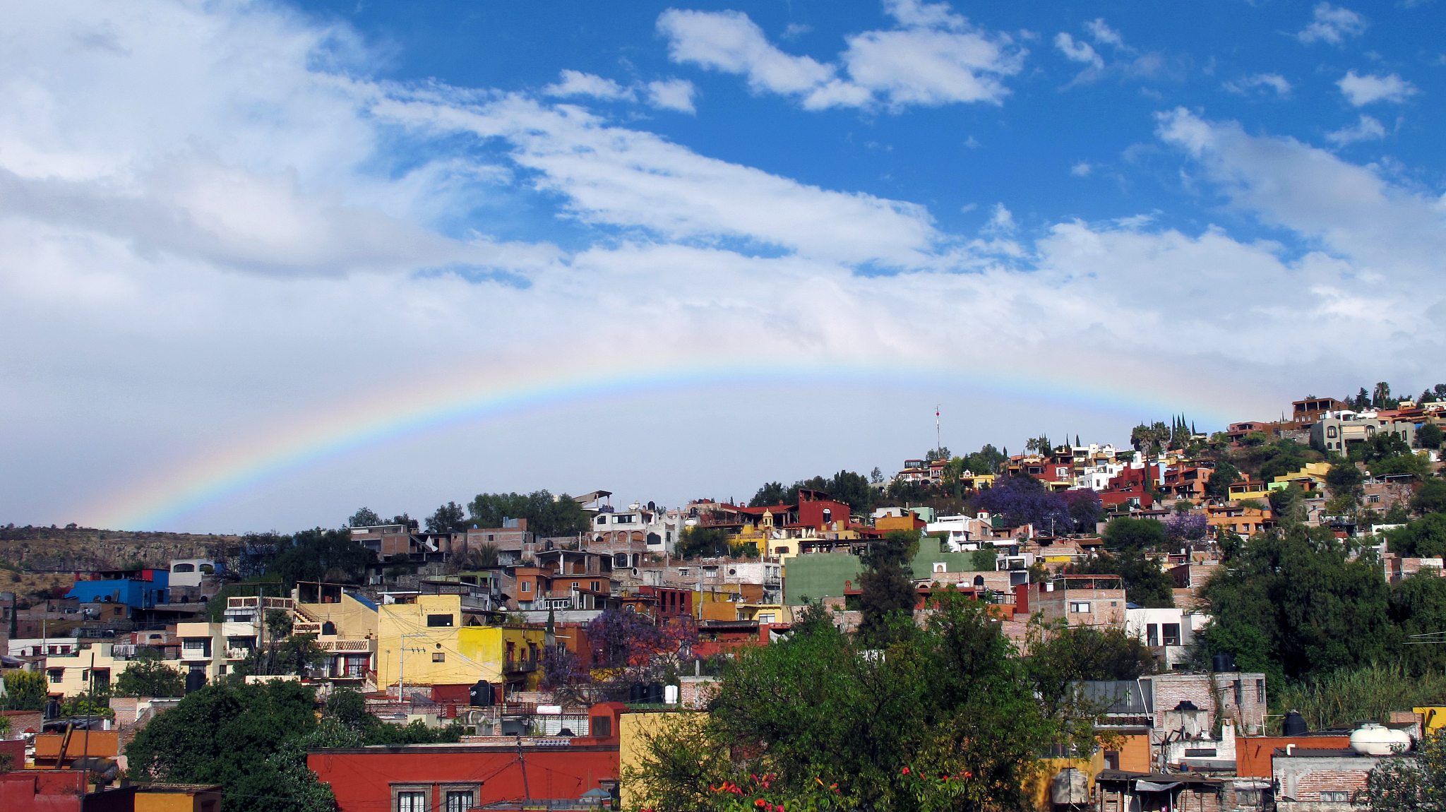 rainbow over buildings in city against sky