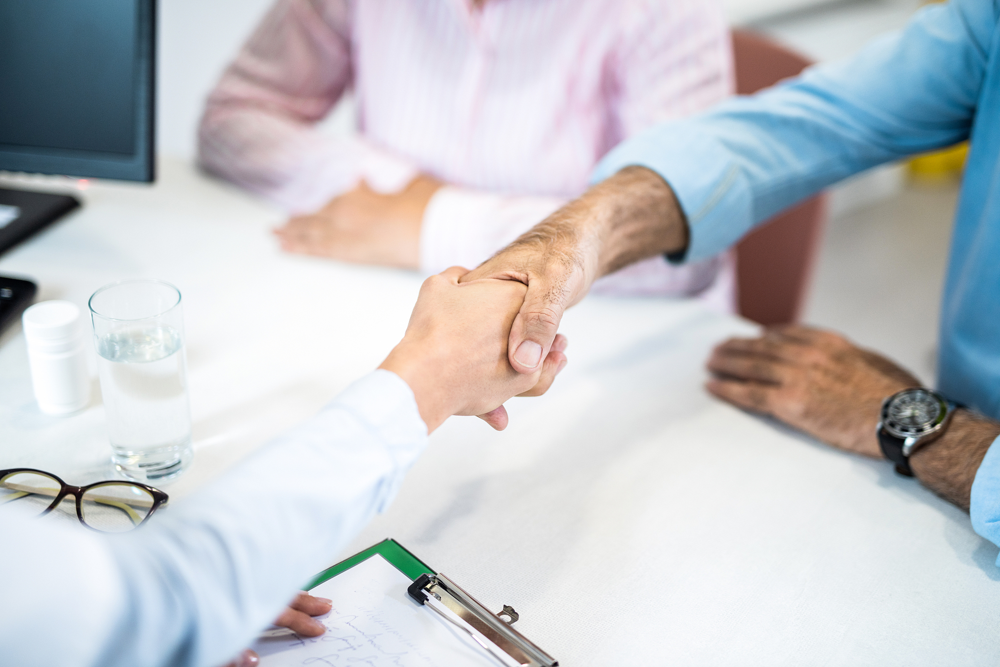 senior man shaking hands with young female doctor.