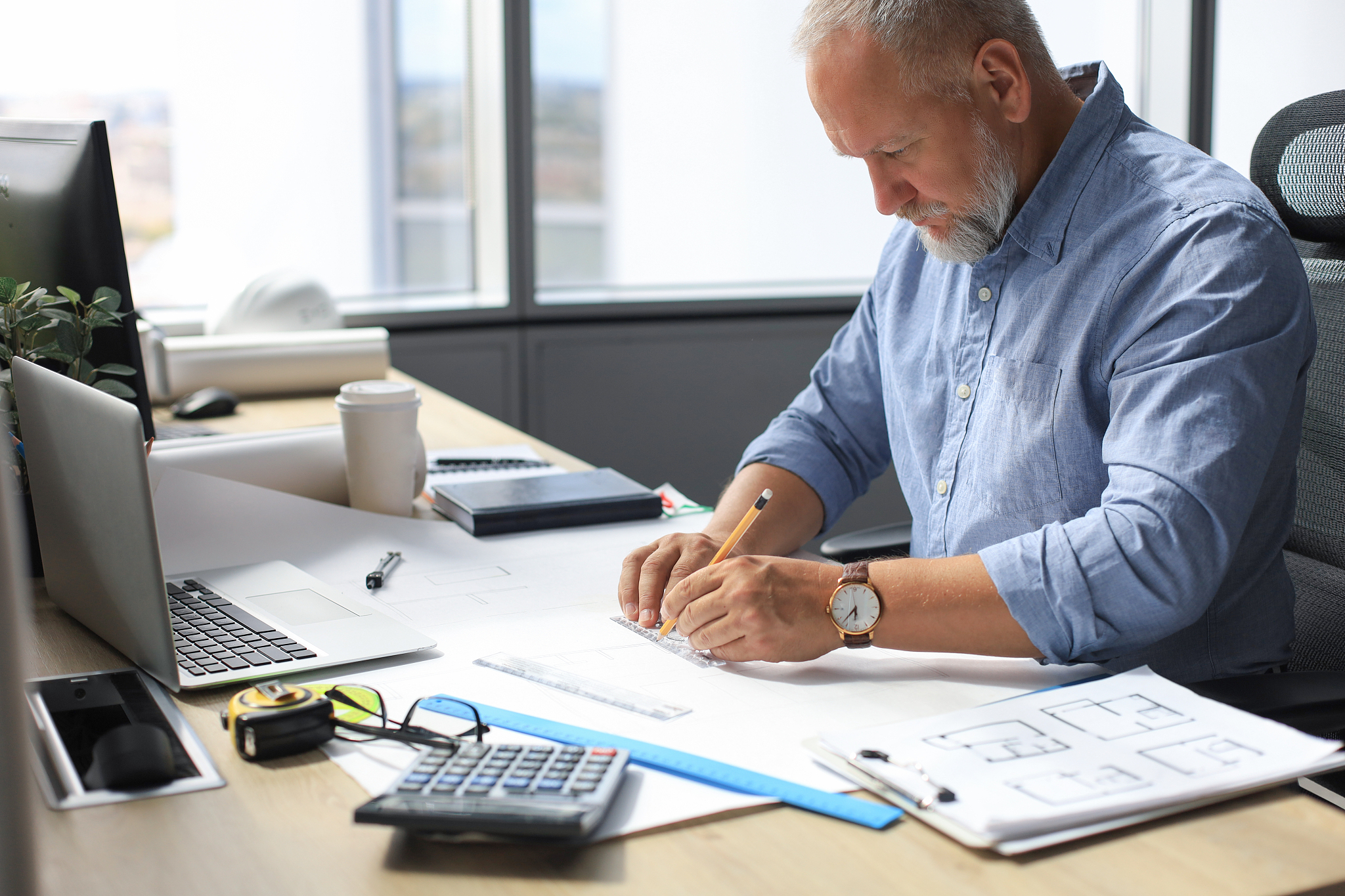 good looking mature architect drawing something while working in