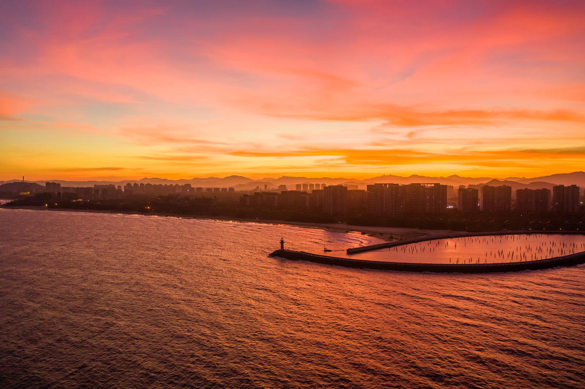 用文艺一点的文字表述一张在深圳湾公园拍摄的照片：在一排高低不齐的高楼大厦中太阳落下只剩下一点余光洒在海面上波光粼粼