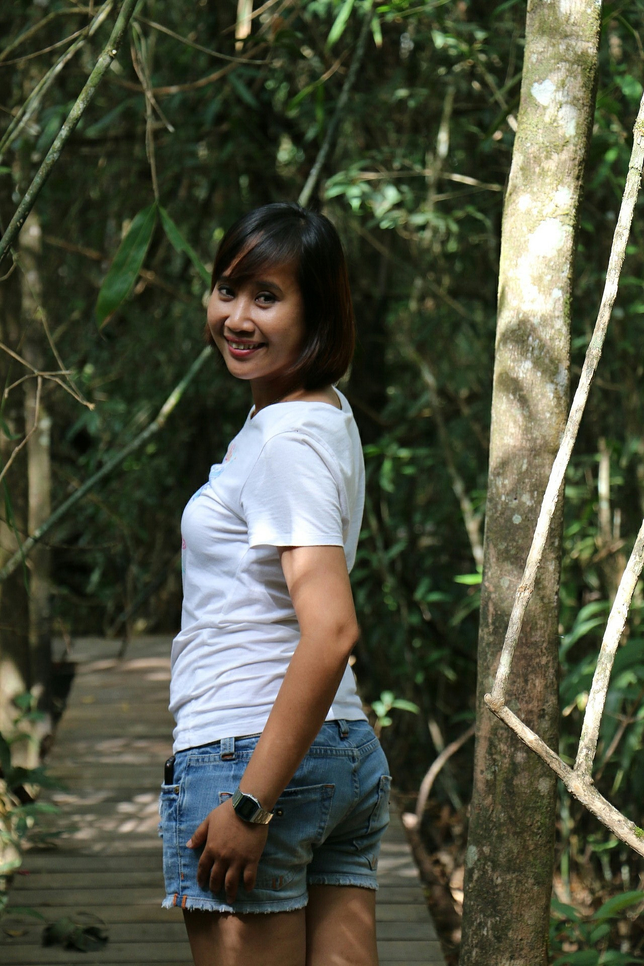 portrait of young woman standing on boardwalk in forest