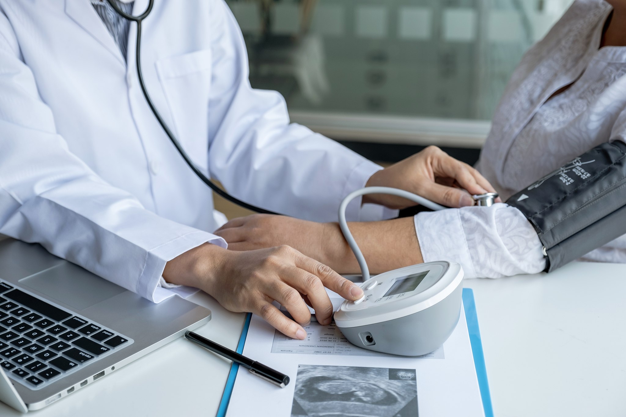 midsection of doctor examining pregnant woman in hospital
