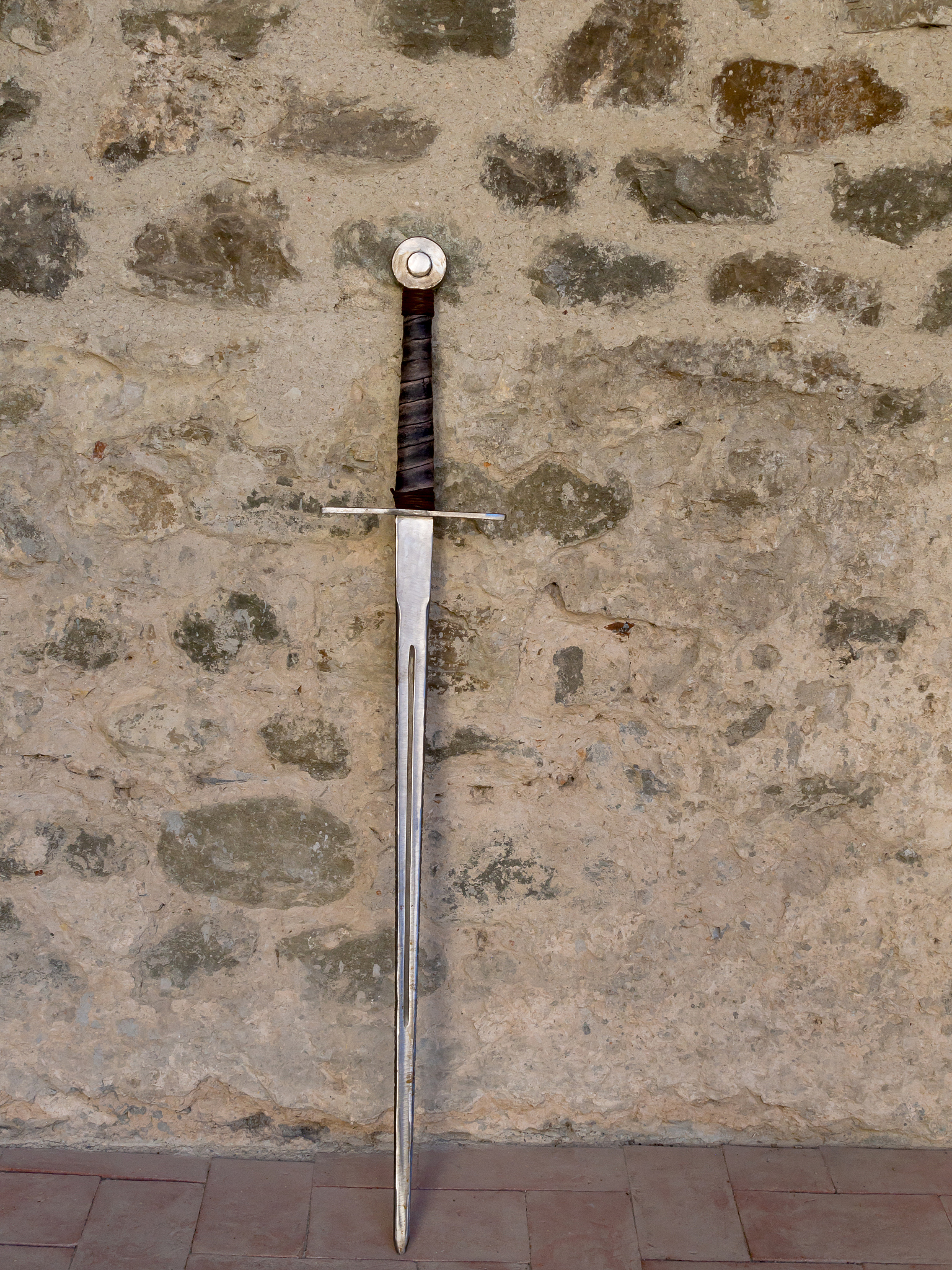 medieval sword leaning on stone wall.