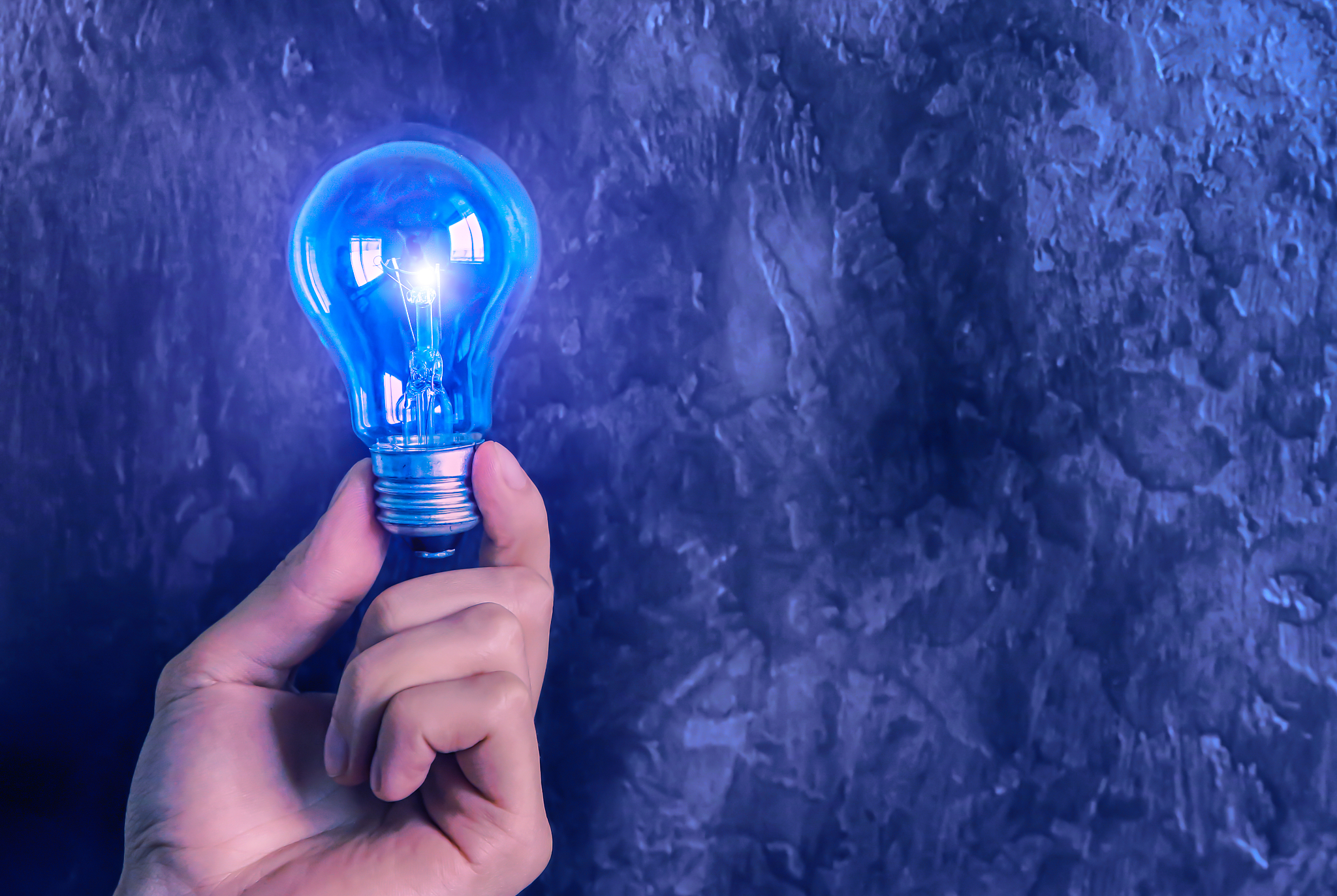 man holding the lamp bulb. new idea concept. blue background.