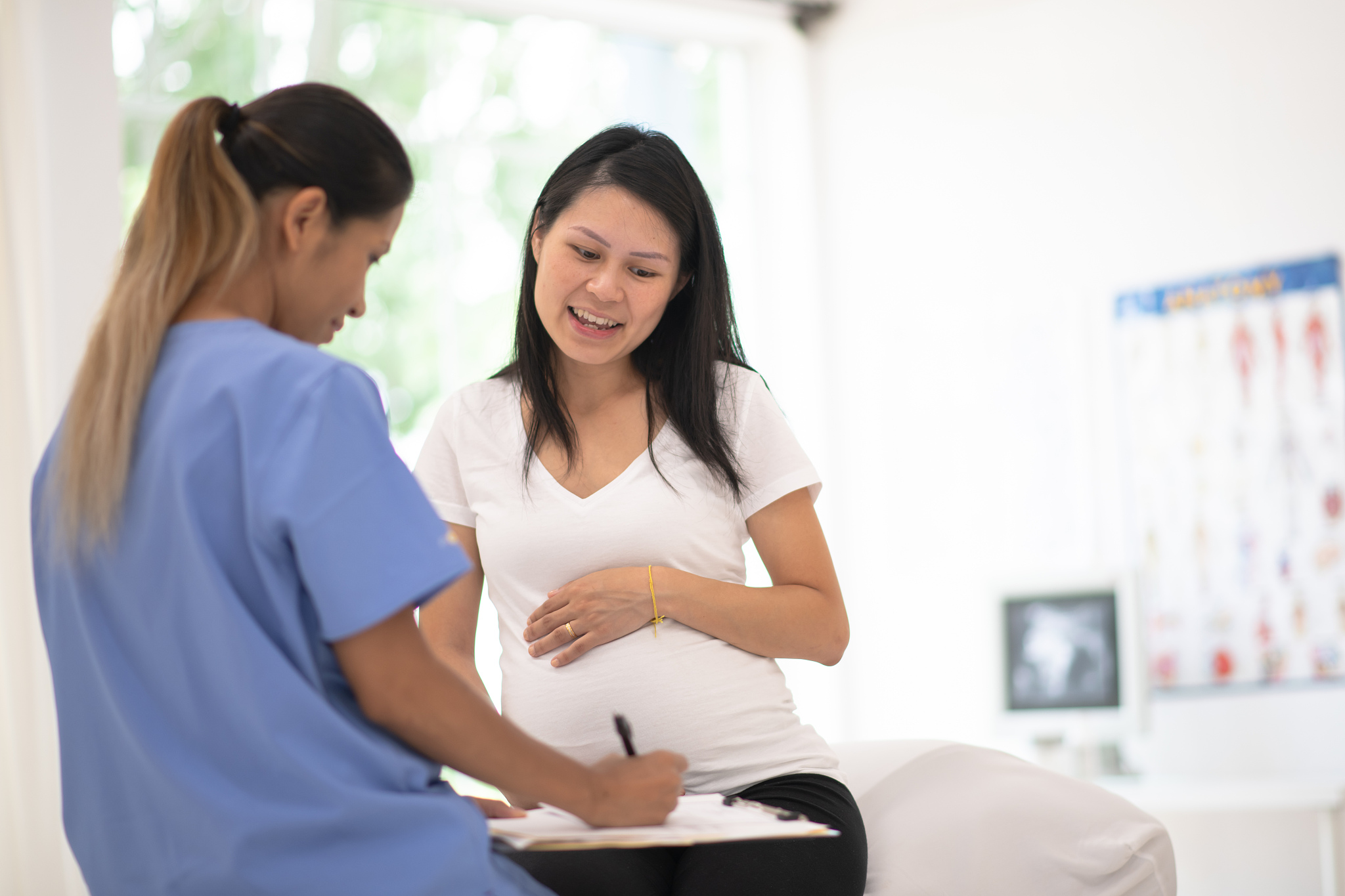 hispanic pregnant woman speaks with her doctor at a check-up sto