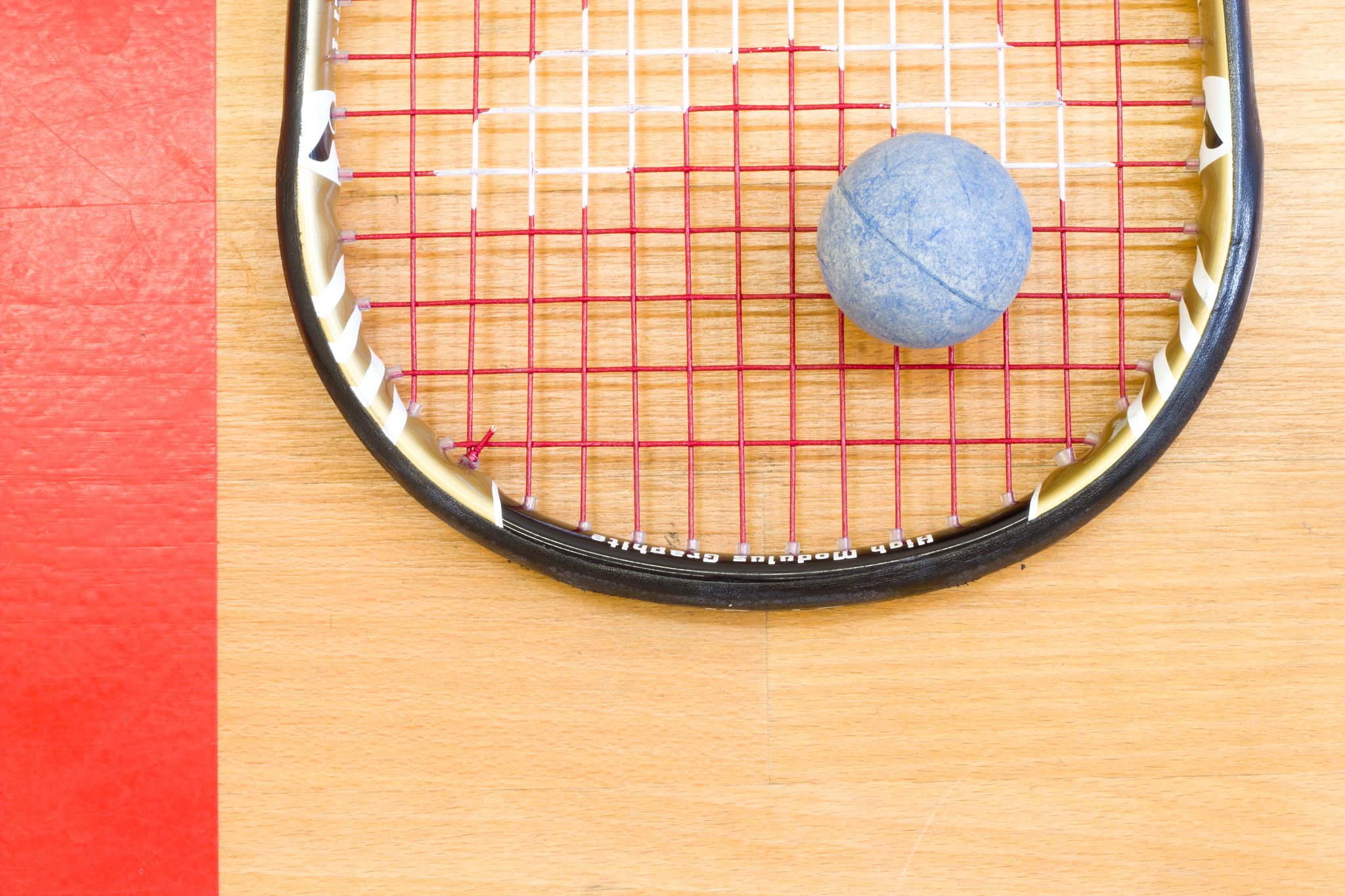 close up of a squash racket and ball on the wooden background