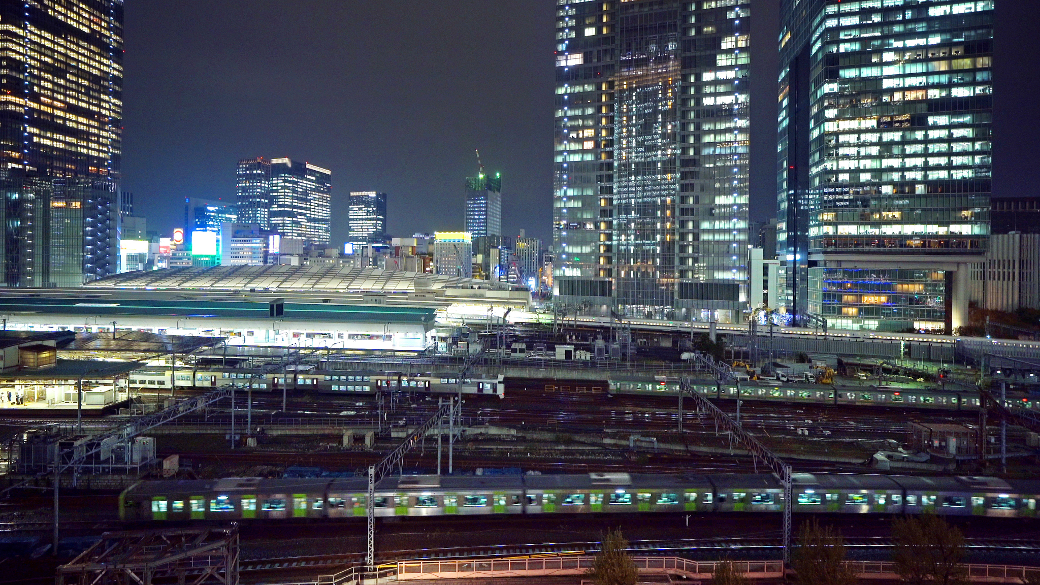 trains in tokyo railway station with high rise buildings. downto