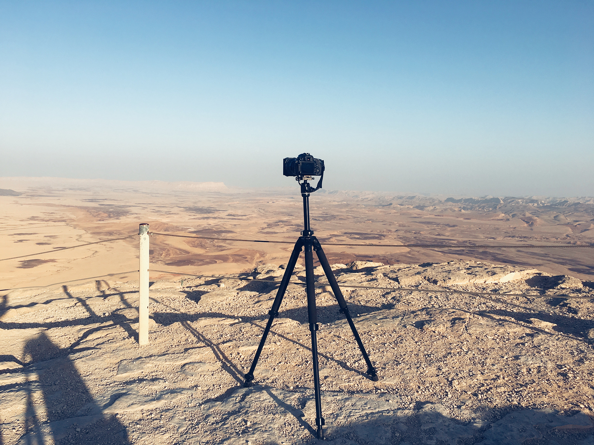 dslr camera maintained on tripod with desert landscape on backgr