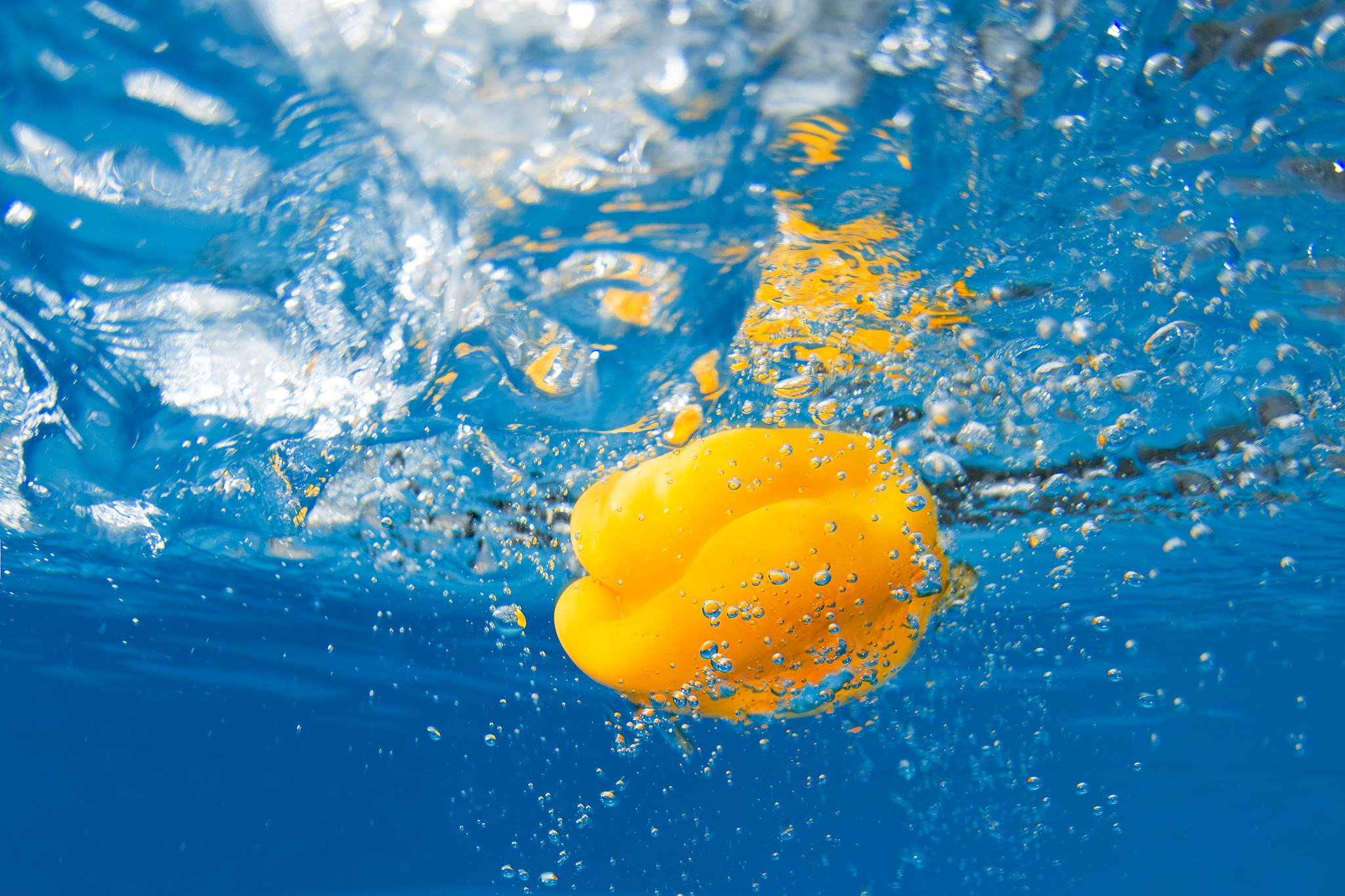 bell pepper splashing in blue water. underwater shot