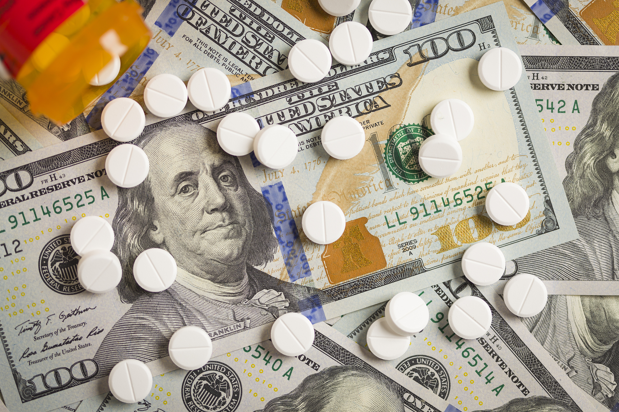 medicine pills scattered on newly designed one hundred dollar bi