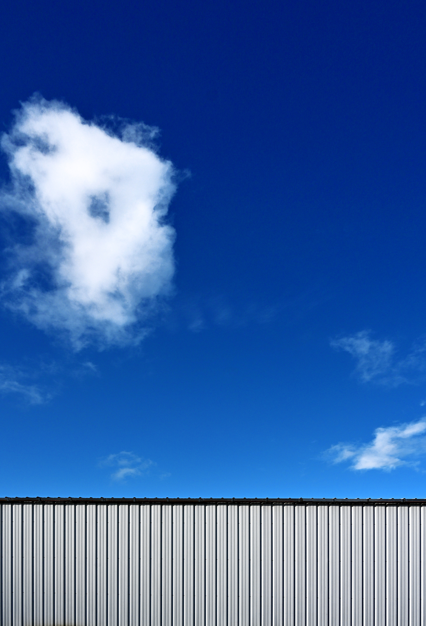 one white cloud deep blue sky and fence