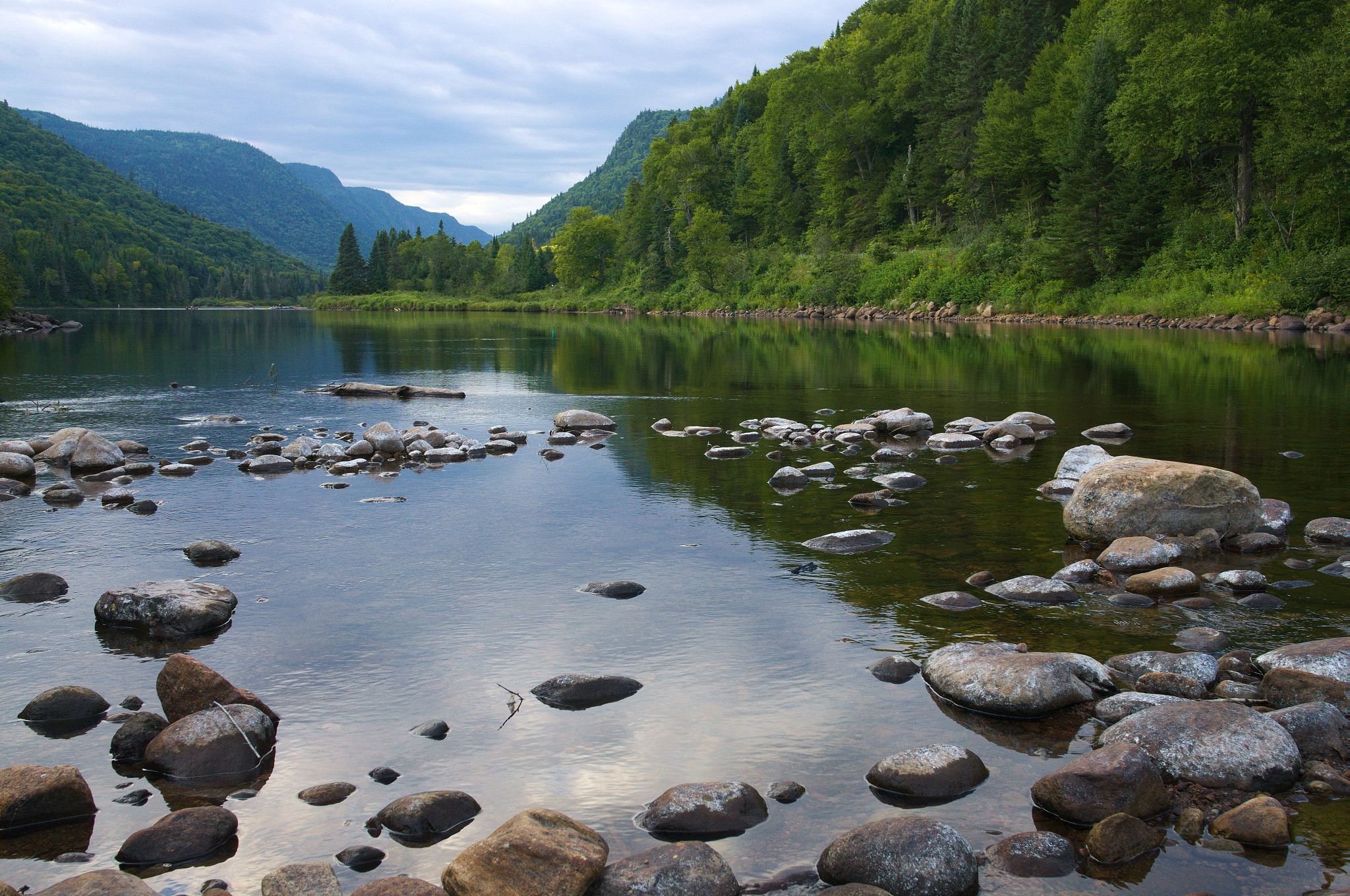 请用100字描述连绵的青山重重叠叠、阴影交叠碧水泛起涟漪的场景。