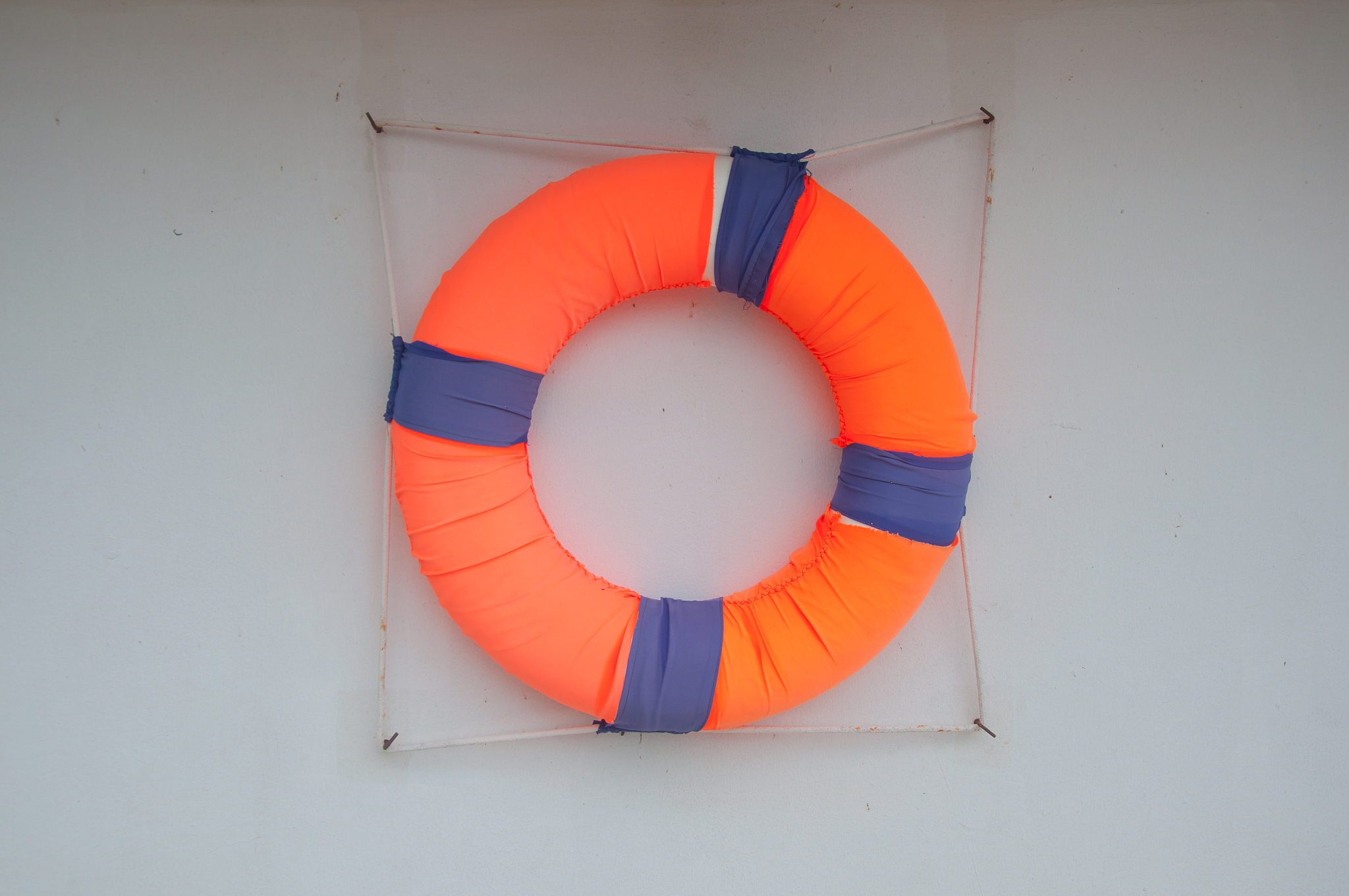 orange lifebuoy hanging on wall of a port building