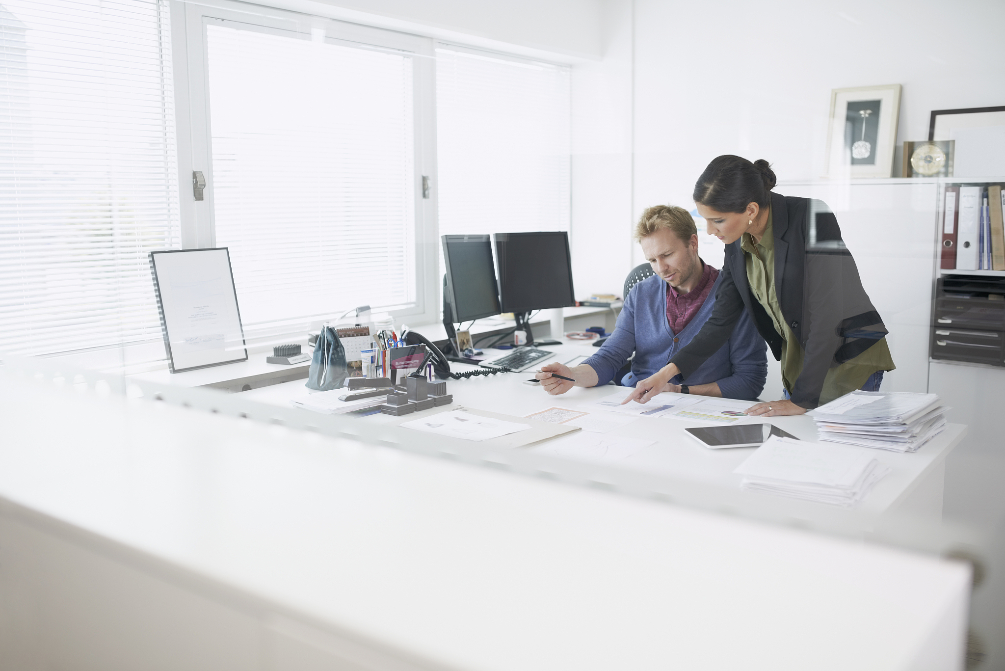 coworkers examining plans at desk in office