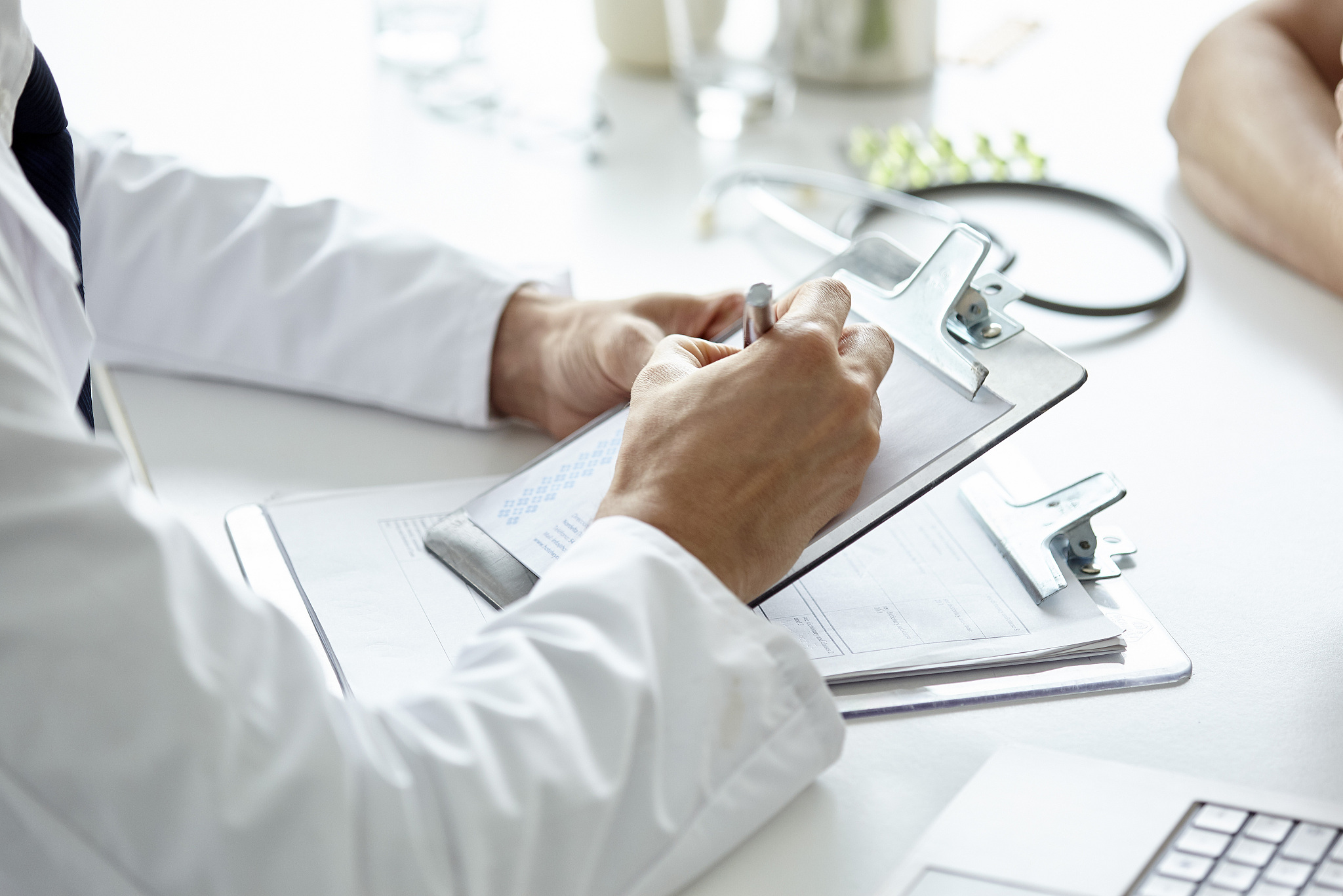 doctor writing prescription on clipboard